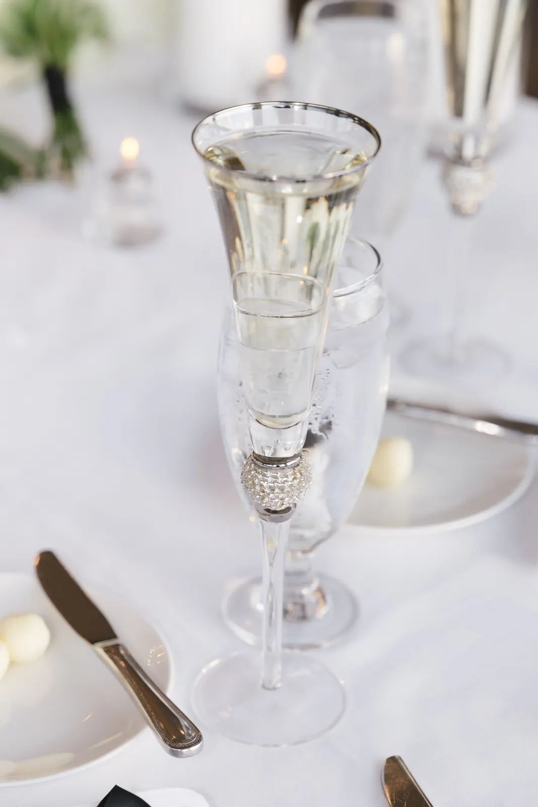 A silver-rimmed champagne flute and place setting at the reception