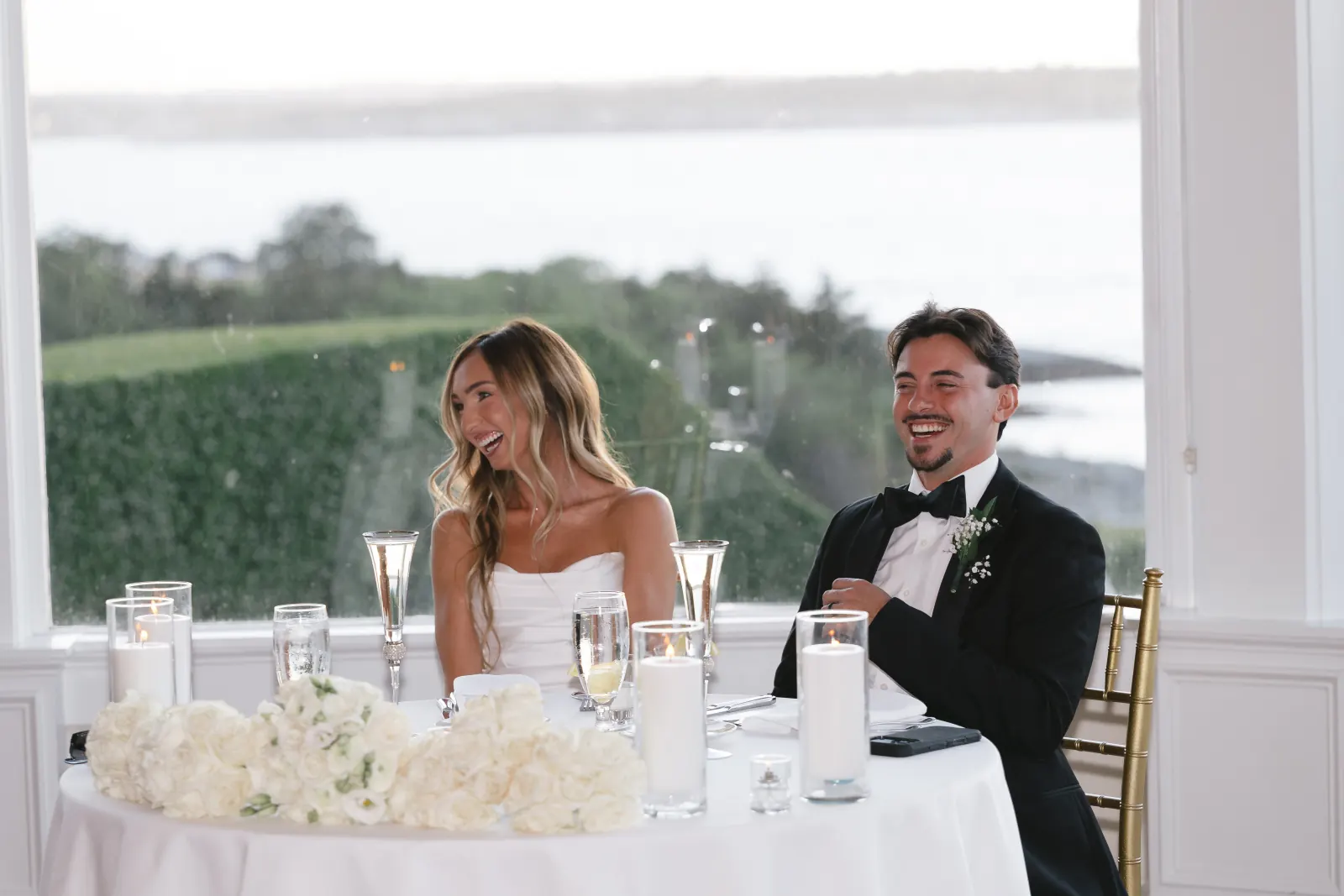 Bride and groom laughing at the sweetheart table with ocean views at OceanCliff