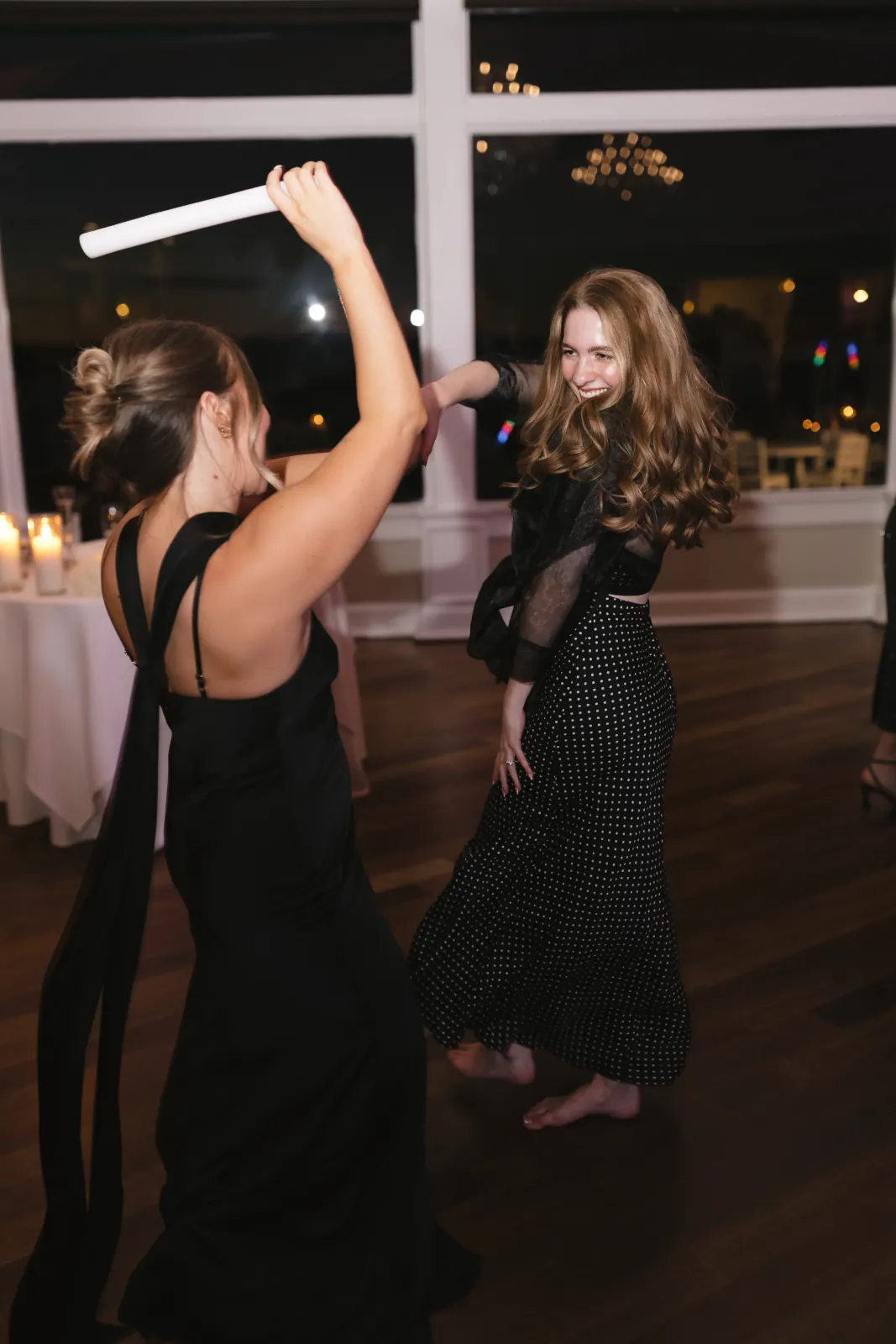 Guests dancing with glow sticks at night, bay windows behind
