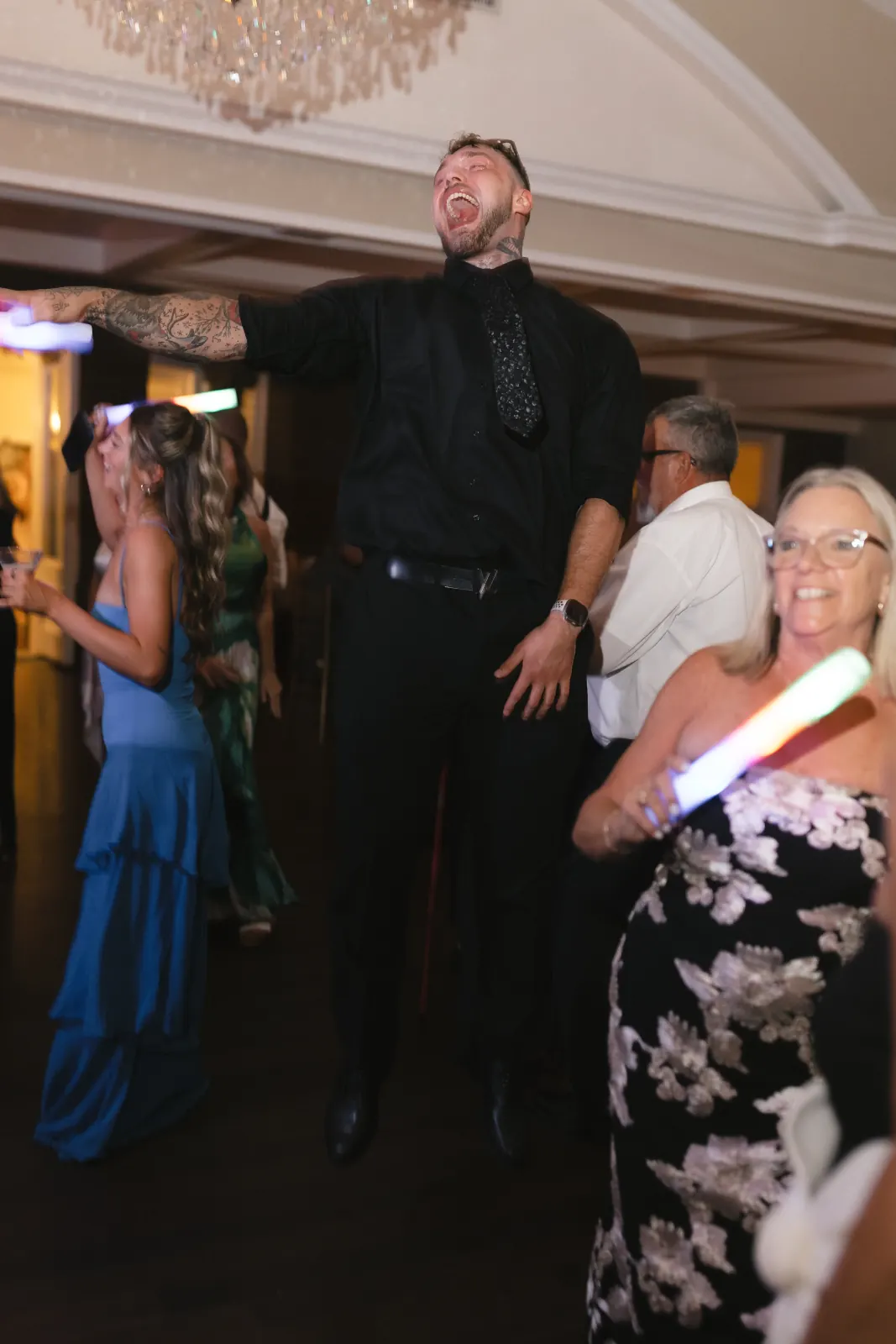 A guest leaps on the dance floor under the chandelier at OceanCliff