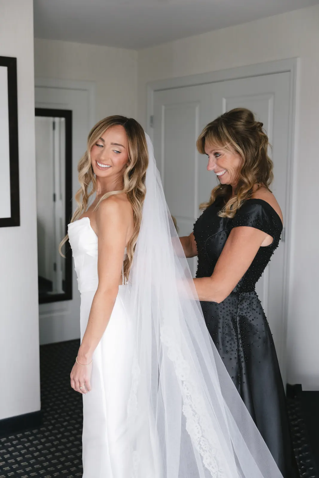 Bride's mother helps her into her cathedral veil while getting ready