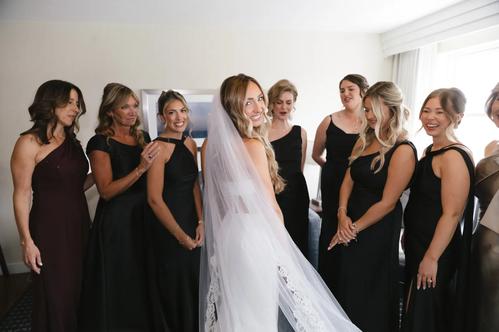 Bridesmaids gather around the bride in her gown and cathedral veil