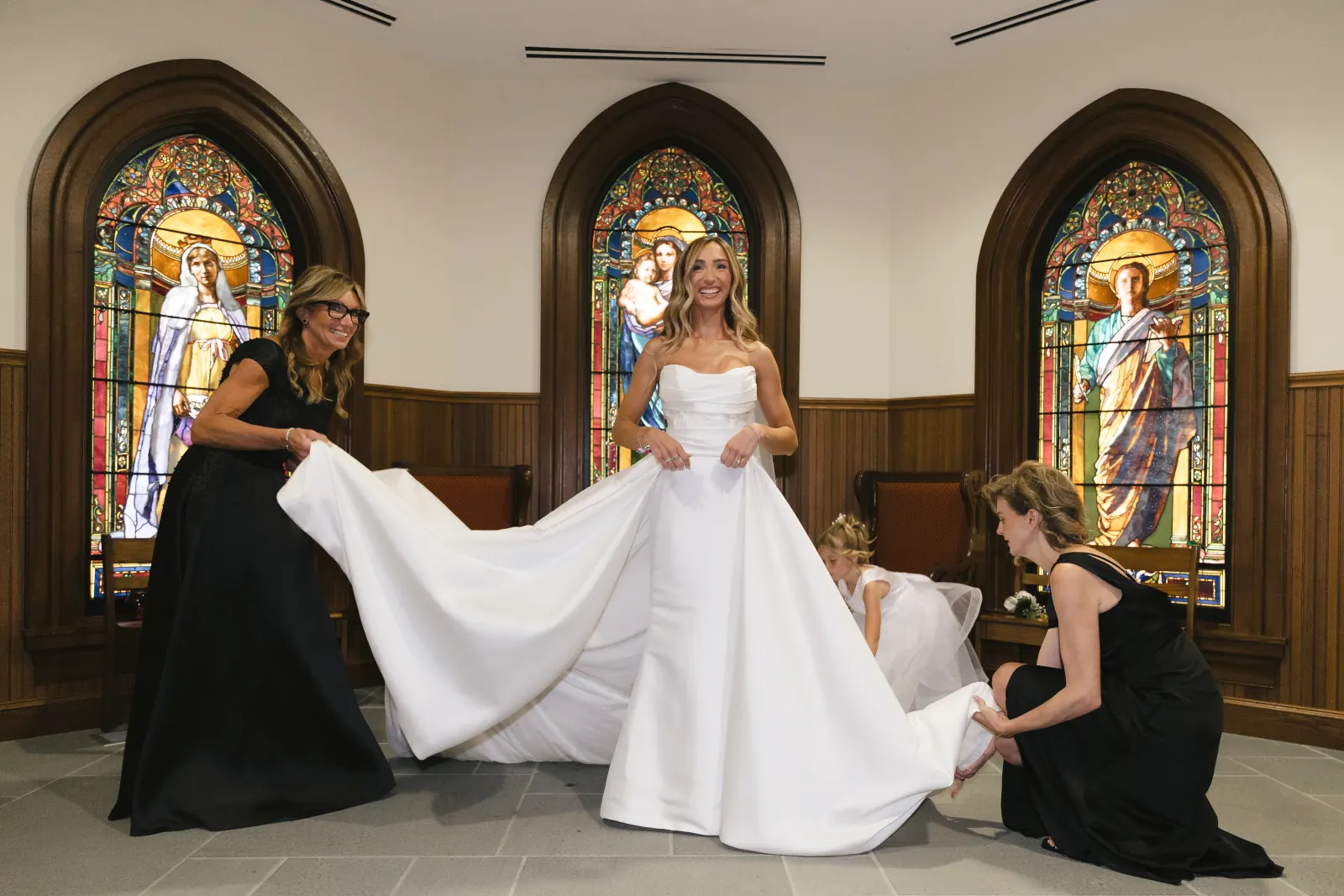 The bride's gown train arranged before the chapel's stained-glass windows