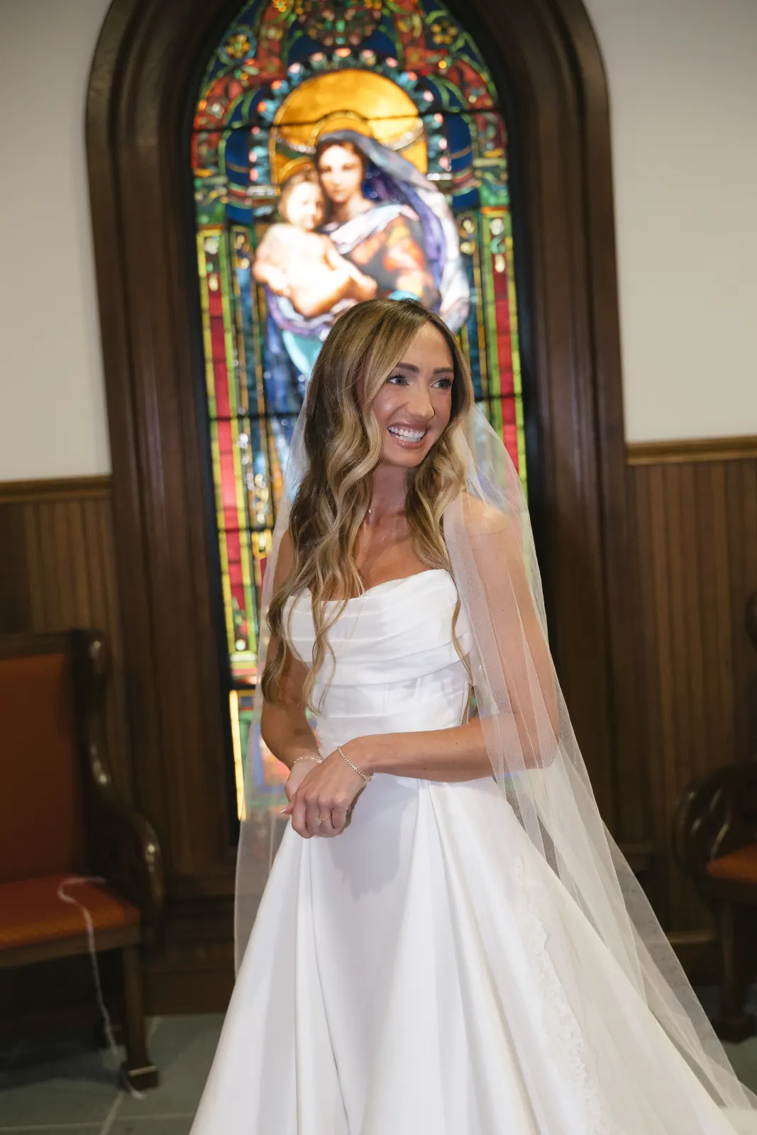 Bride before the stained-glass Madonna window at Our Lady of Mercy Chapel