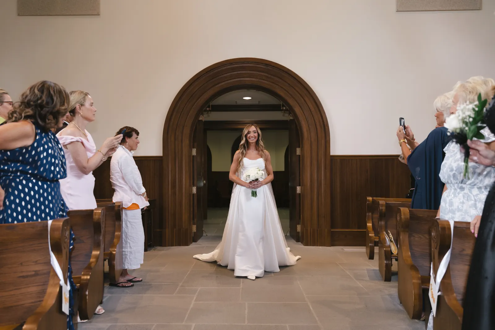 The bride enters Our Lady of Mercy Chapel as guests rise, Newport wedding ceremony