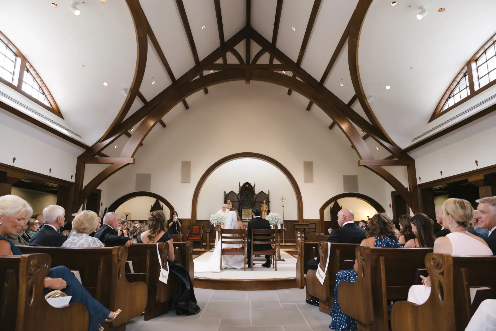 Wide view of the wood-beamed Our Lady of Mercy Chapel during the wedding ceremony