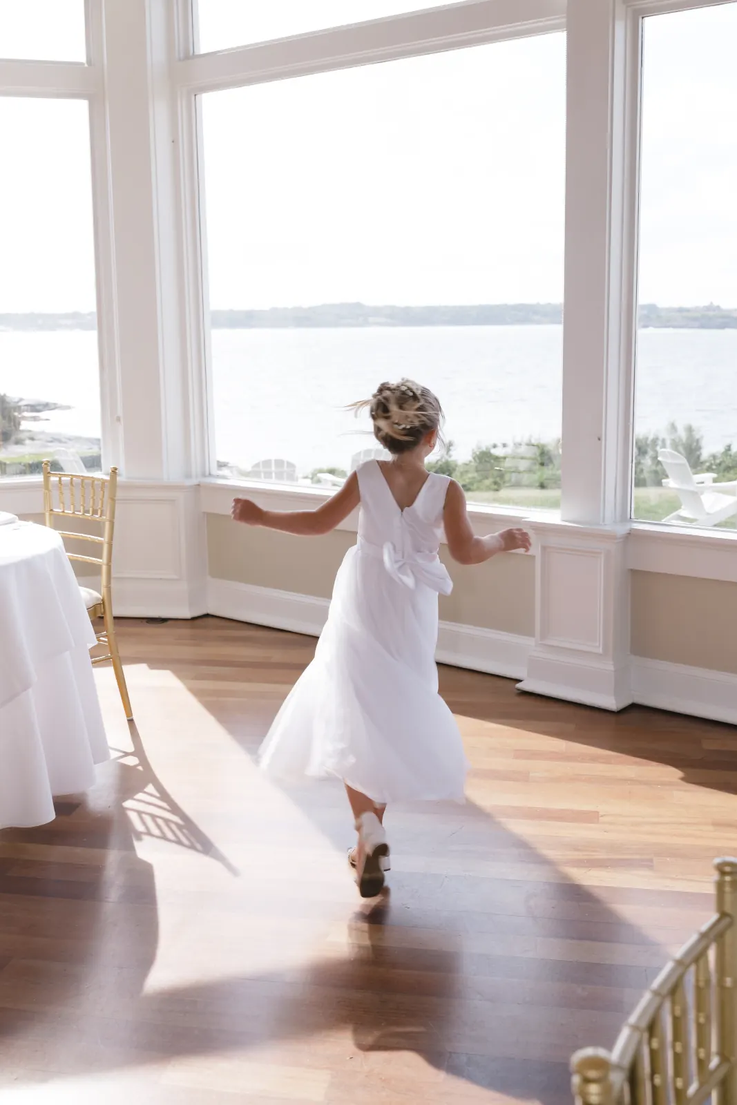 The flower girl runs through the bay-view ballroom at OceanCliff