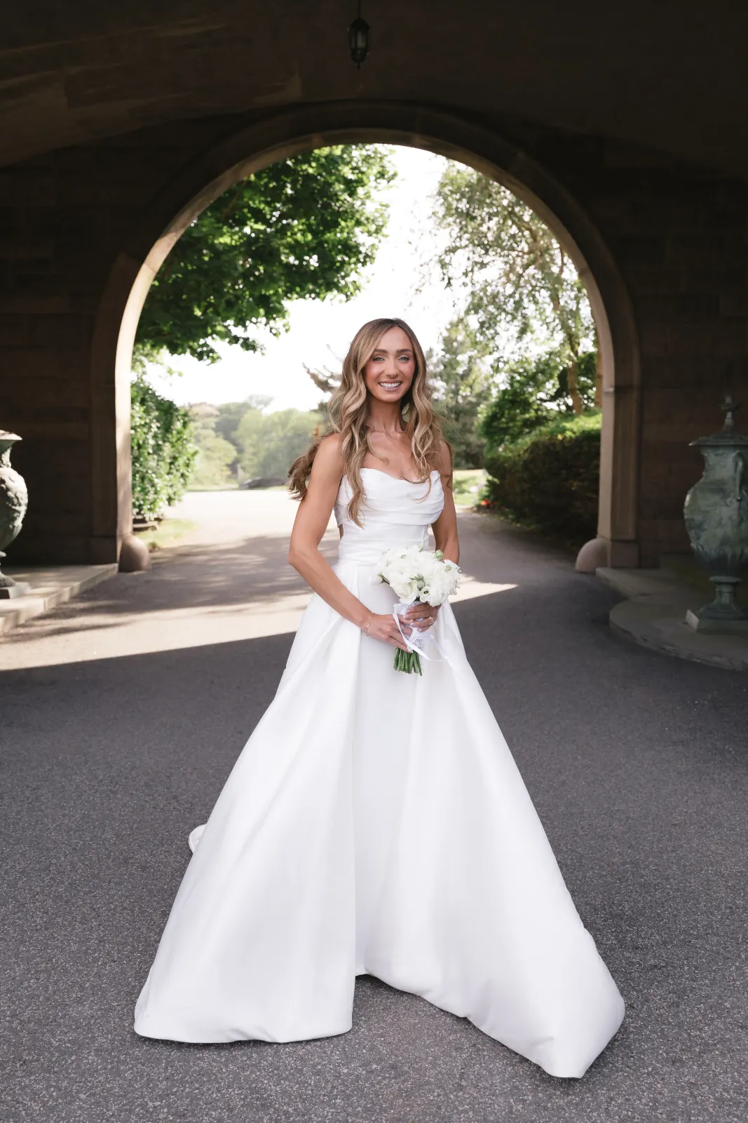Bride beneath the OceanCliff stone archway with her bouquet