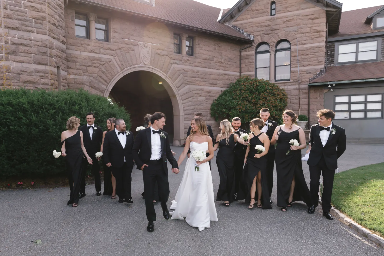 Bride, groom and bridal party walk by the OceanCliff stone archway