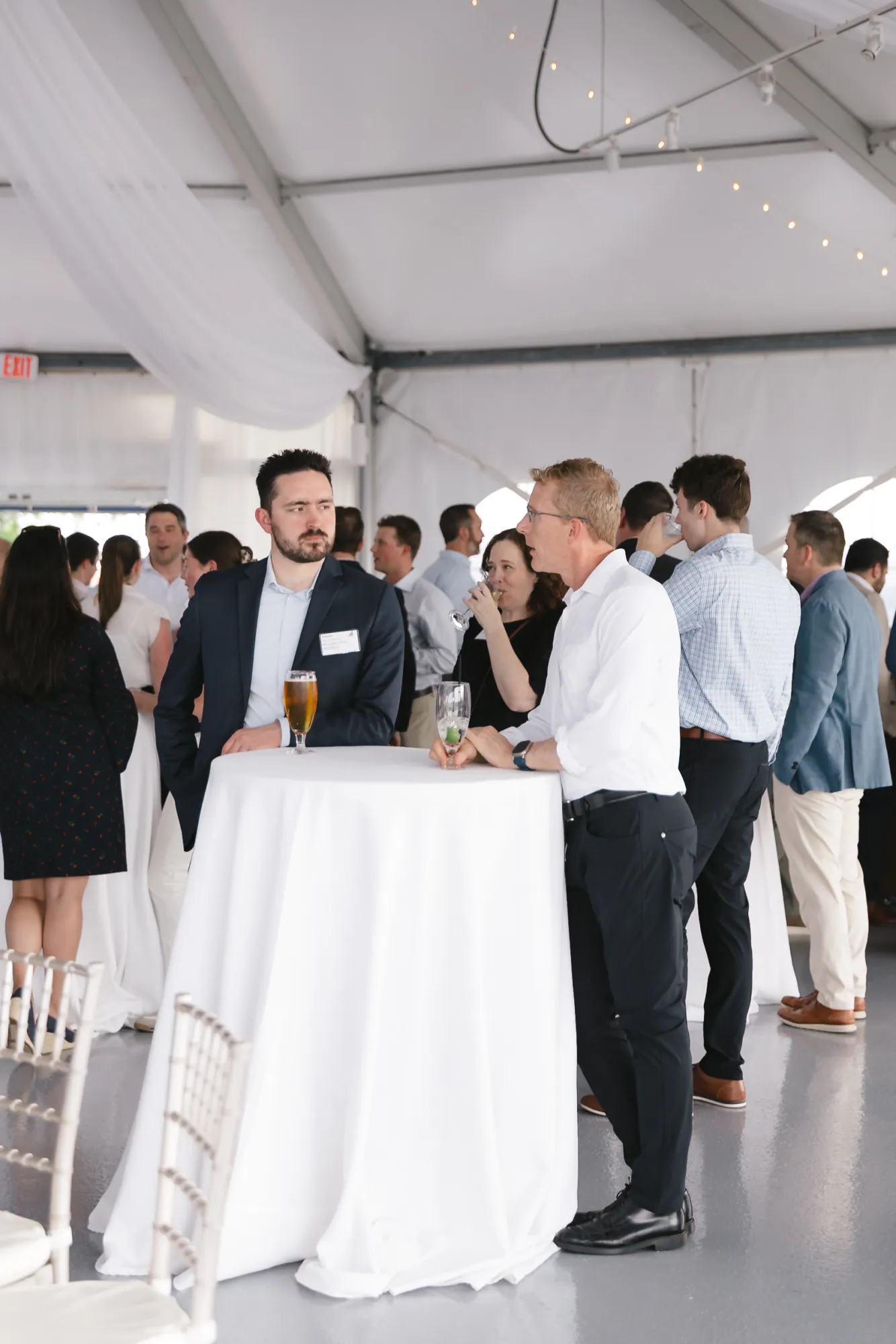 Two attendees networking over drinks at a cocktail table under string lights during the CFMA event at Granite Links, Quincy MA