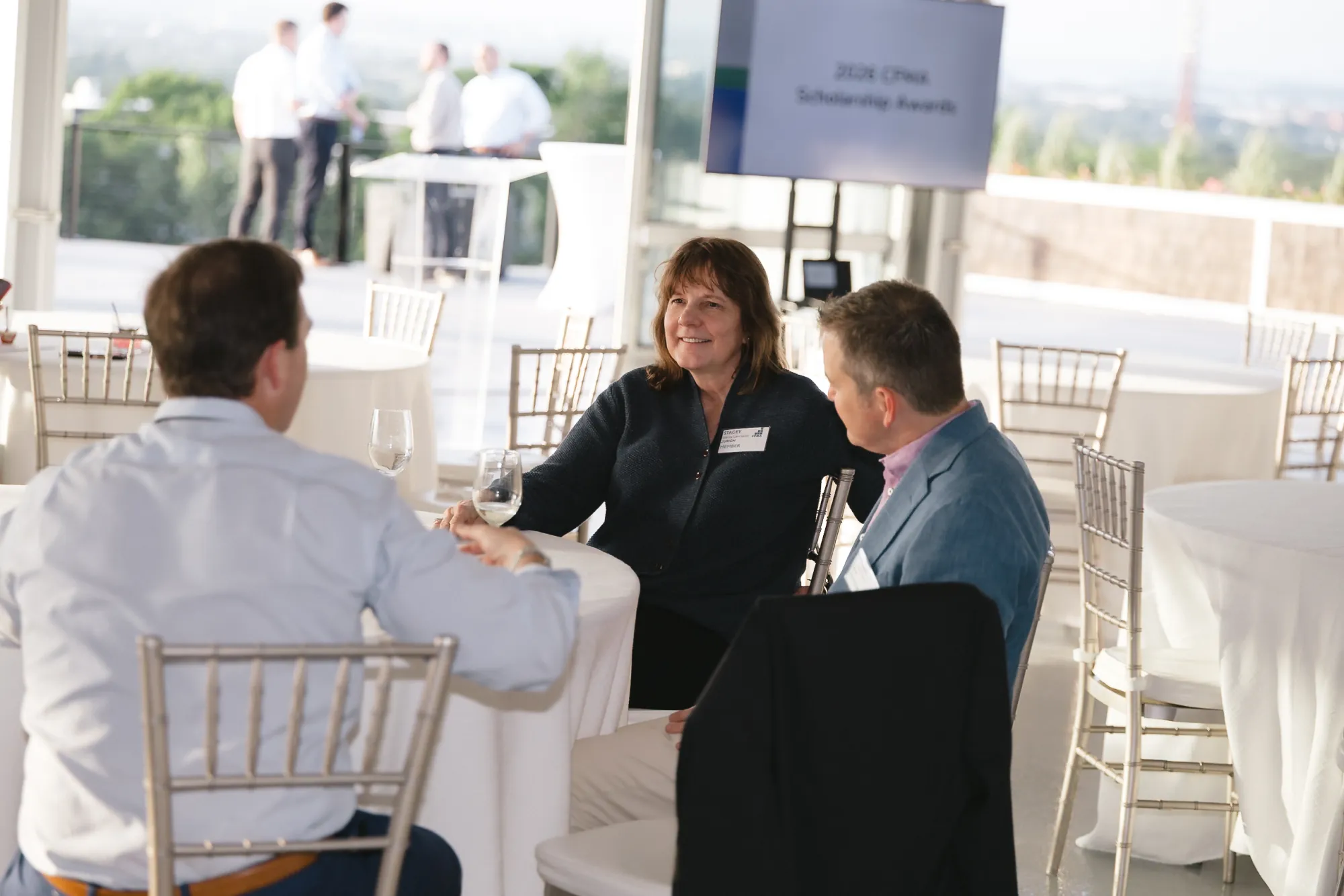 Members in conversation in front of the 2026 CFMA Scholarship Awards screen at the Granite Links event, Quincy MA
