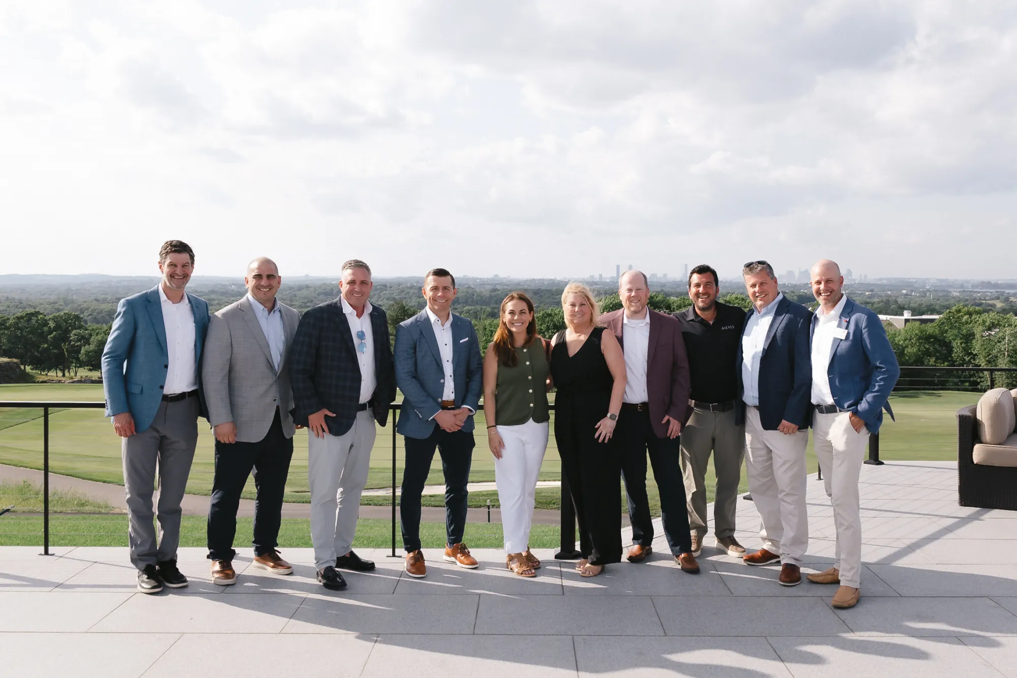Group portrait of CFMA members on the Granite Links terrace with the golf course and Boston skyline behind them, Quincy Massachusetts