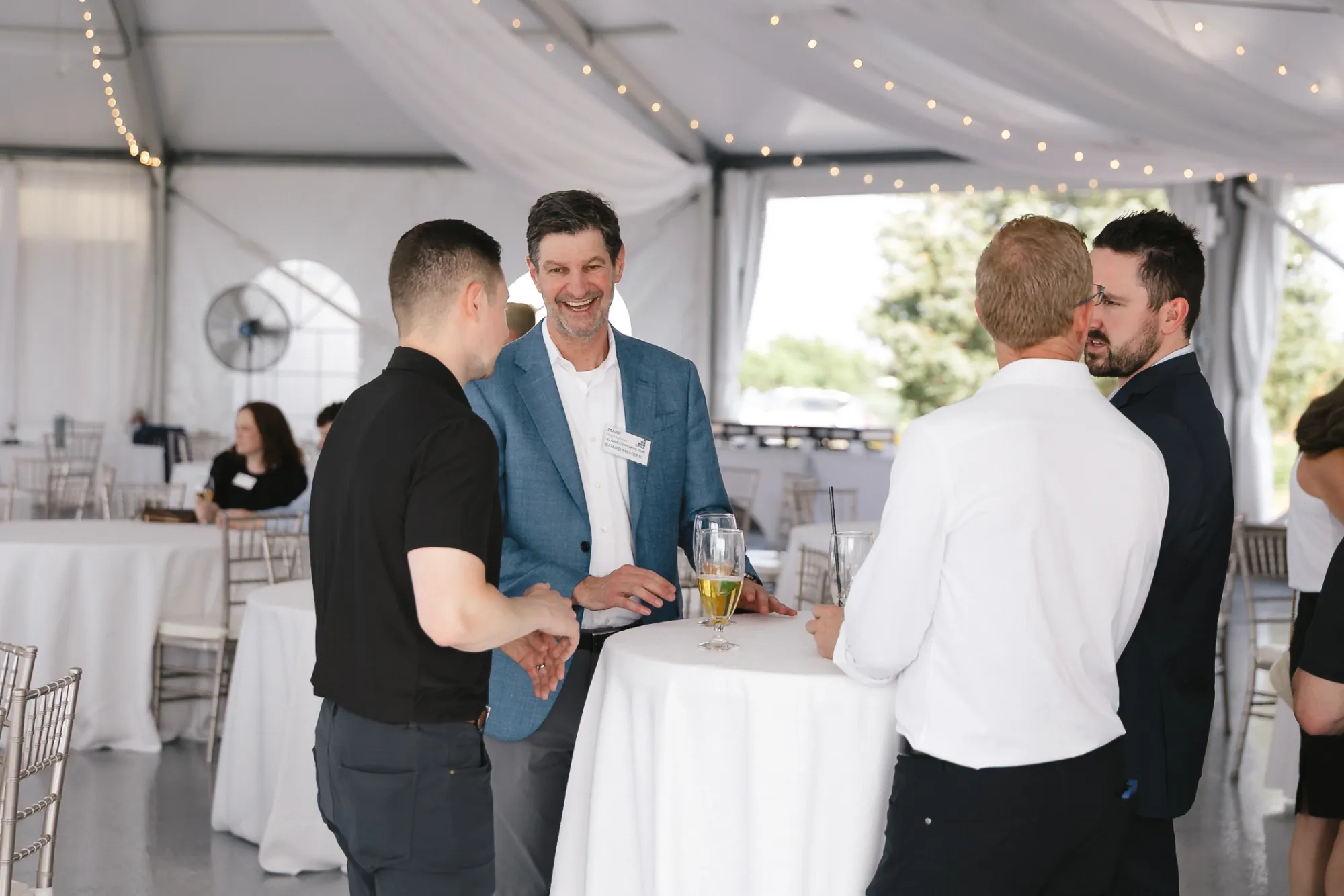 Construction finance professionals networking and shaking hands at a cocktail table during the CFMA reception at Granite Links, Quincy MA