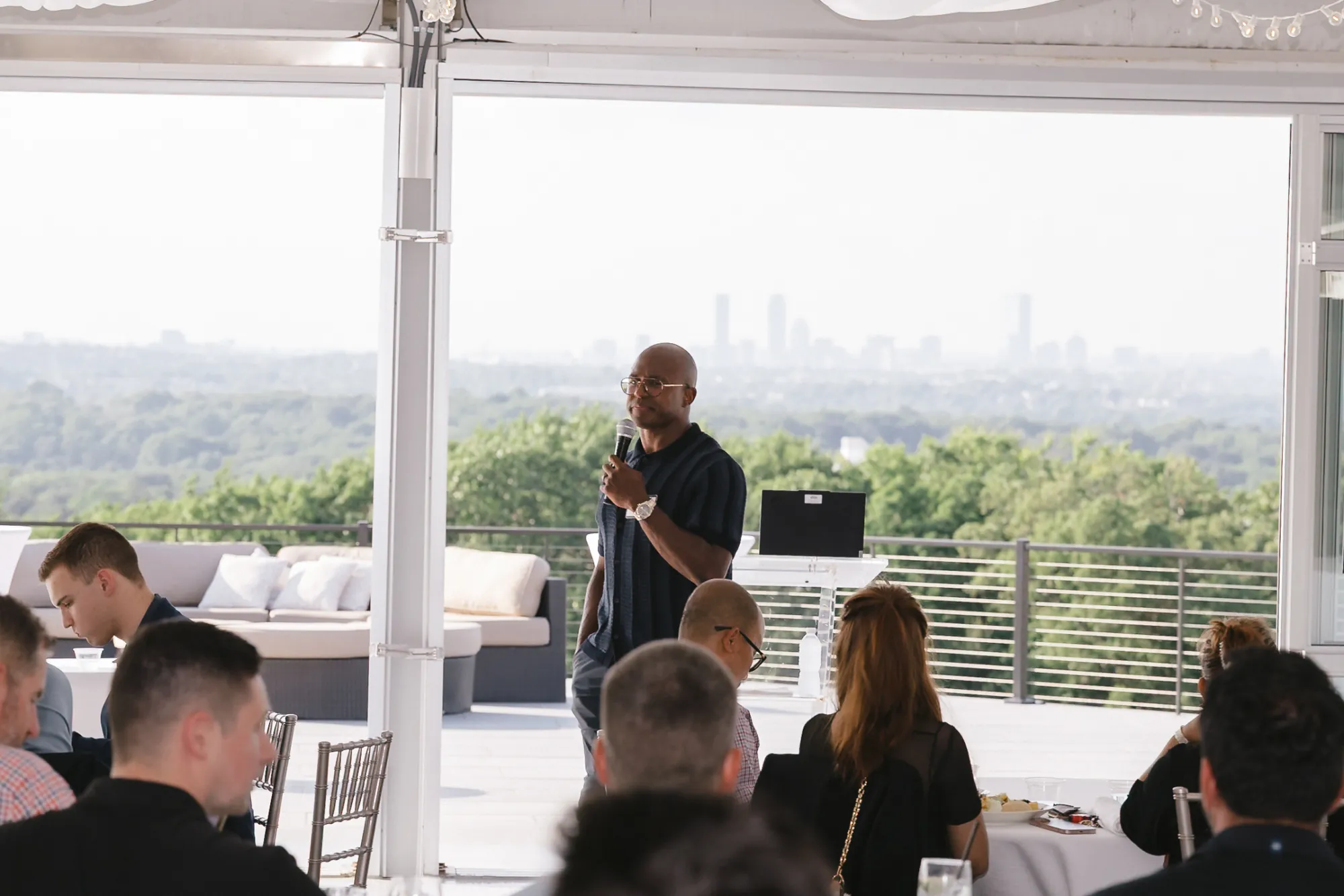 Matthew Slater giving his keynote in front of the open tent wall overlooking the Boston skyline at Granite Links Golf Club, CFMA event, Quincy MA