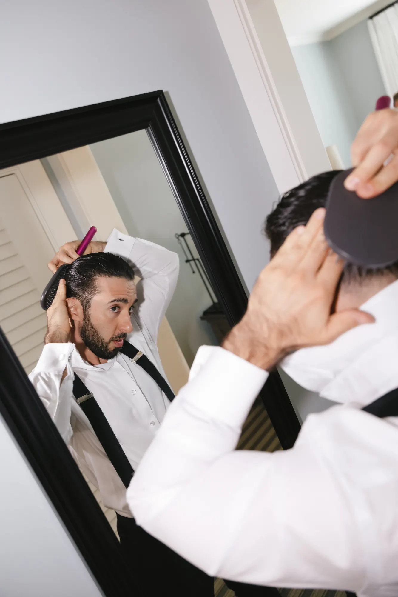 Groom gets a fresh trim in the mirror on the wedding morning