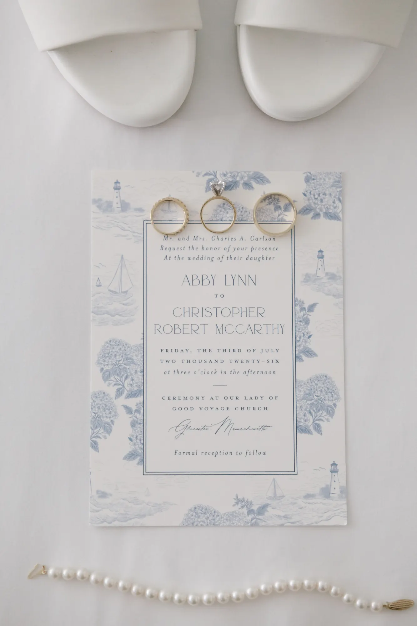 Wedding invitation suite with rings, pearl necklace, and the bride's white heels