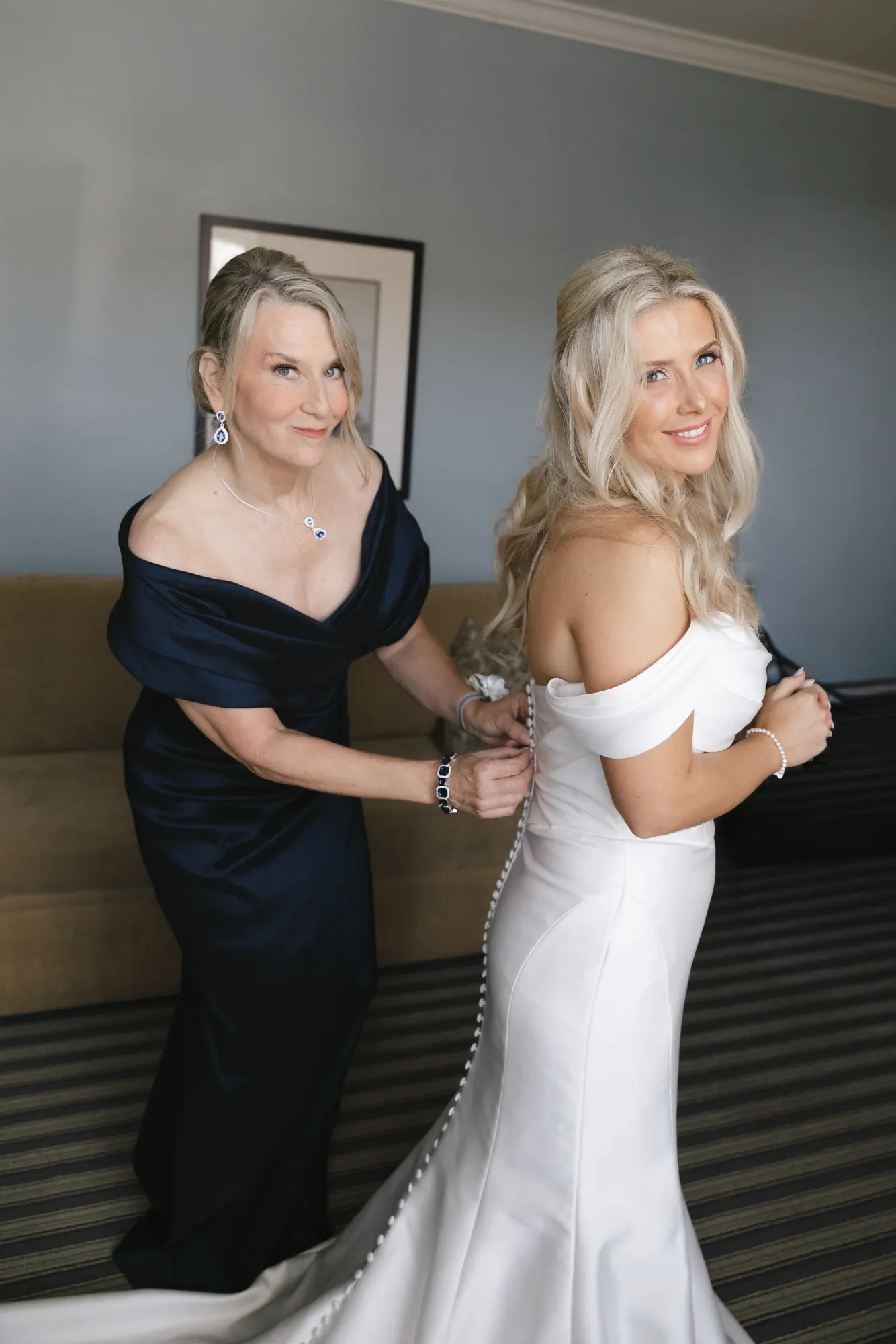 The bride's mother in navy helps her with her bracelet before the ceremony