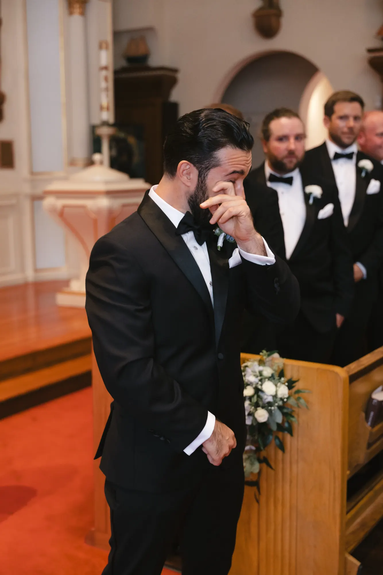 Groom wipes away a tear as the bride enters the church