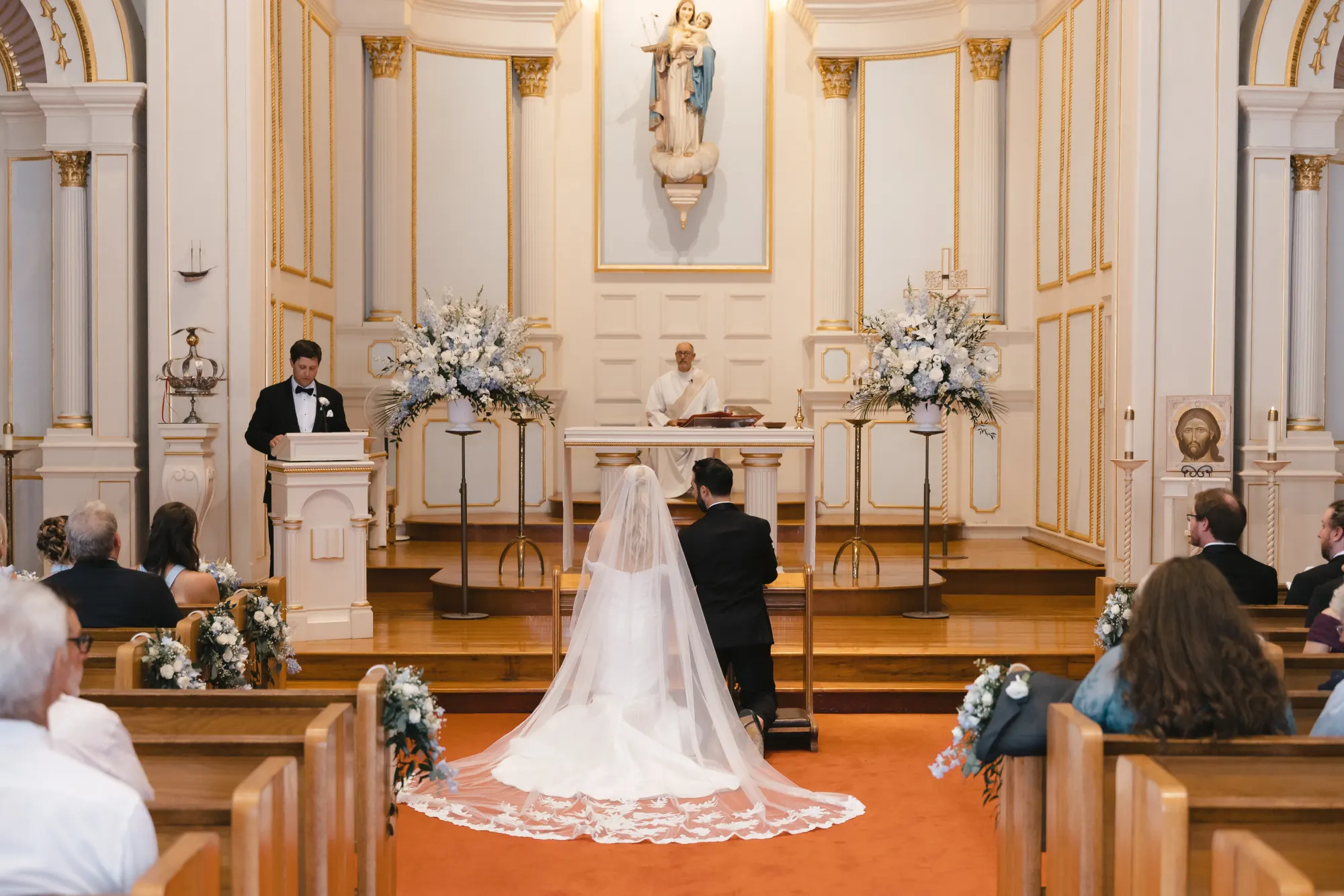 Wedding ceremony at Our Lady of Good Voyage, the bride's lace-edged veil spread down the aisle