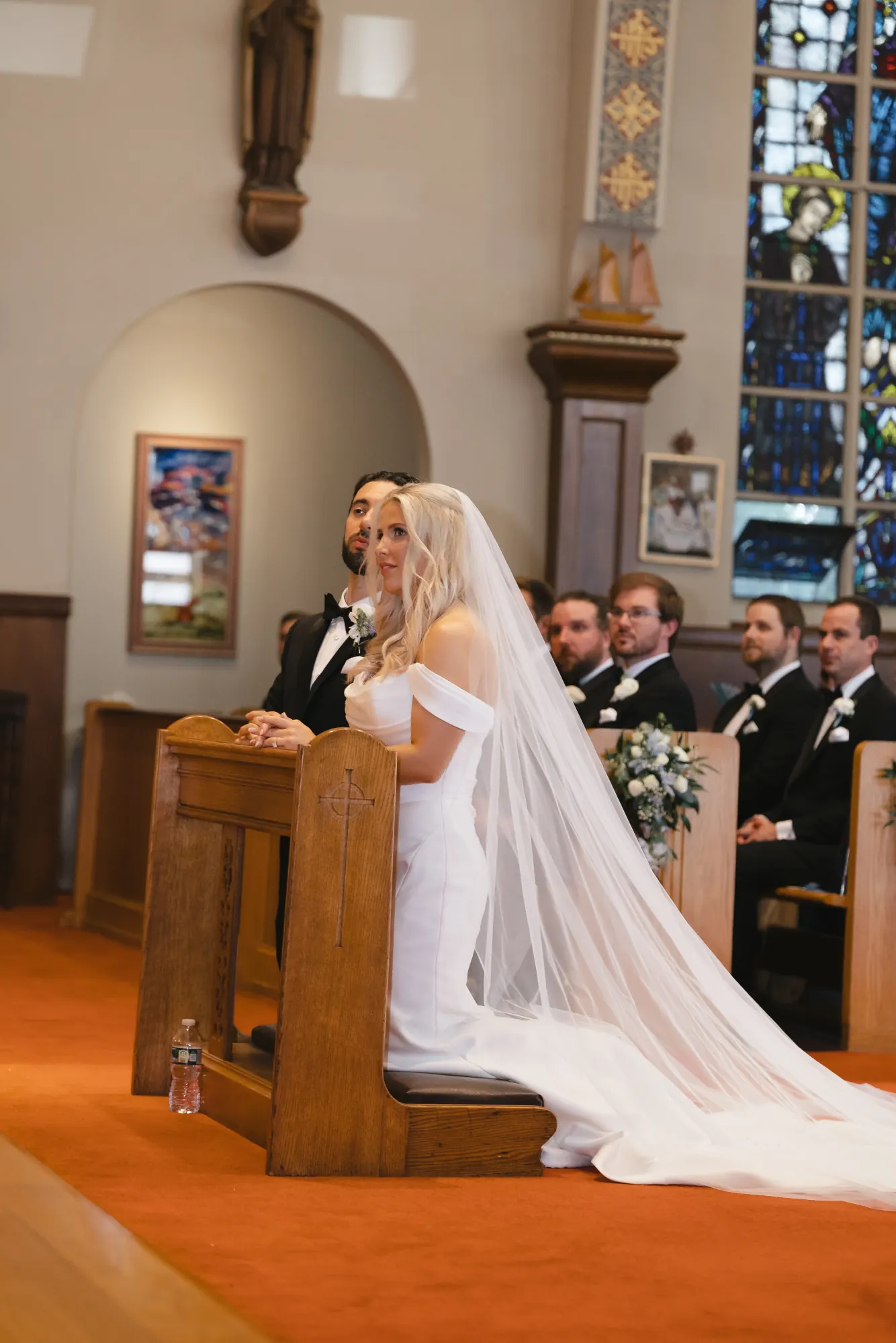 Bride and groom kneel side by side during the Catholic ceremony