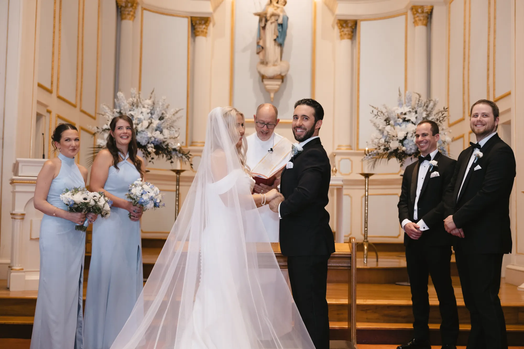 The couple exchange rings as the wedding party looks on