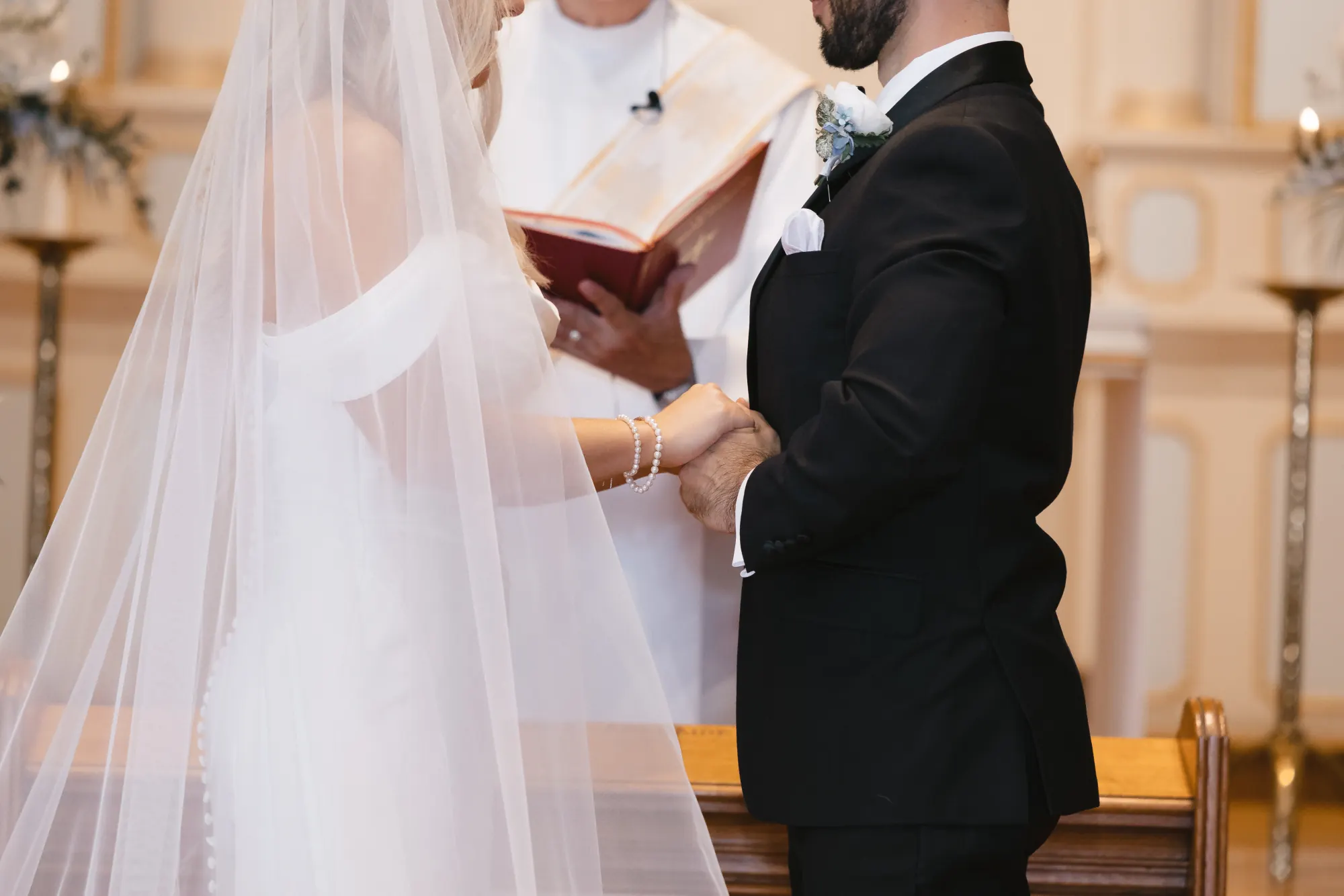 Close detail of hands and veil during the ring exchange