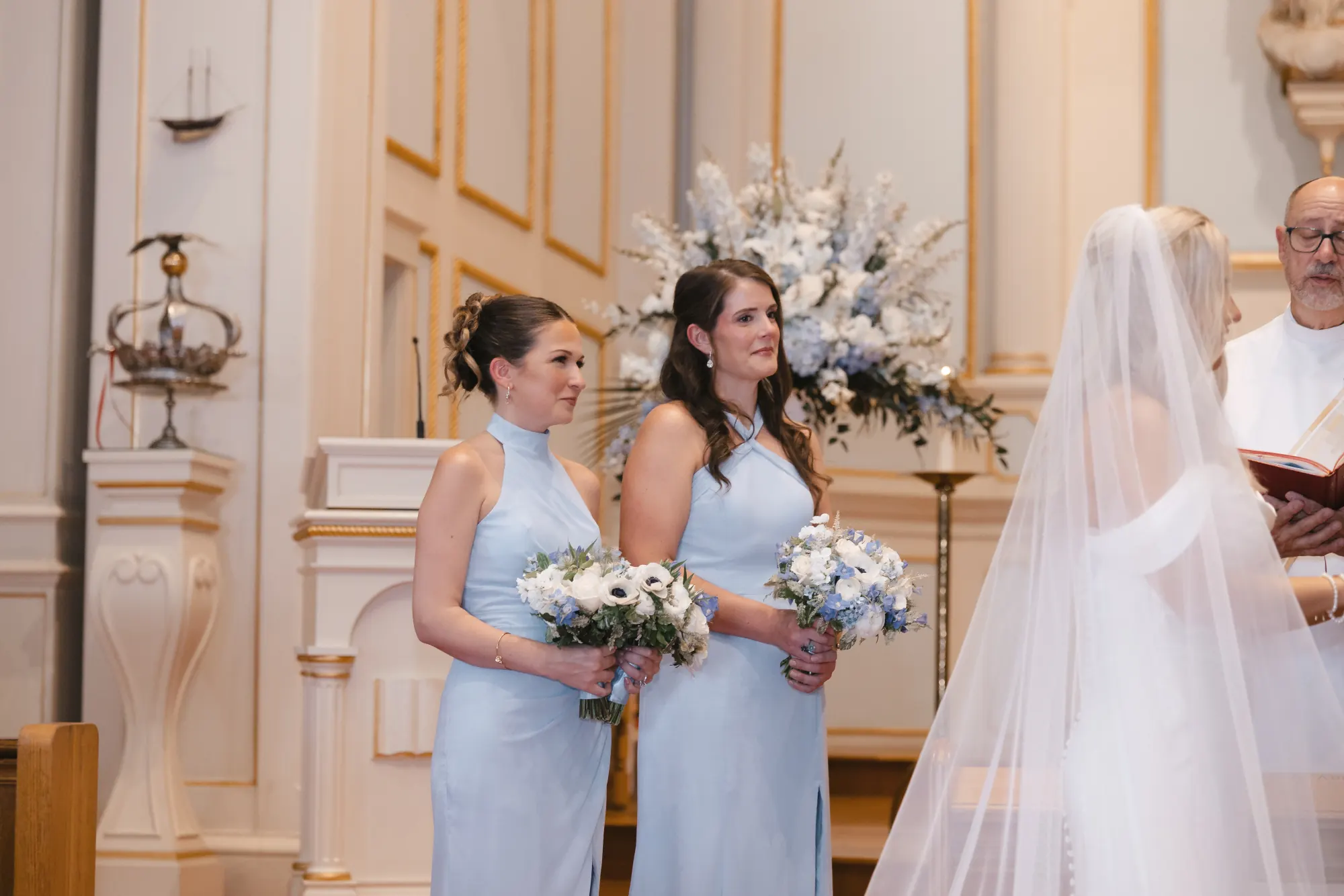 Bridesmaids in light blue watch the vows with their bouquets
