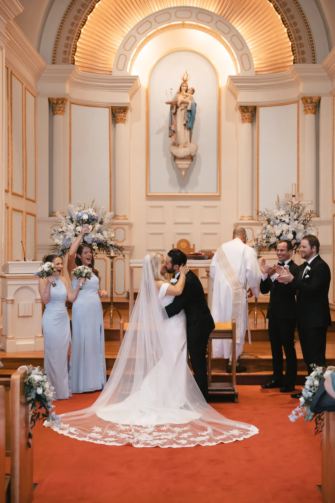 The first kiss at the altar, flanked by the wedding party