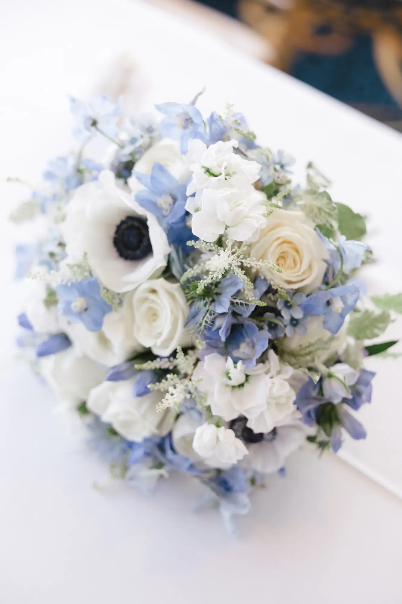 The bride's bouquet of white roses, anemones, and blue delphinium