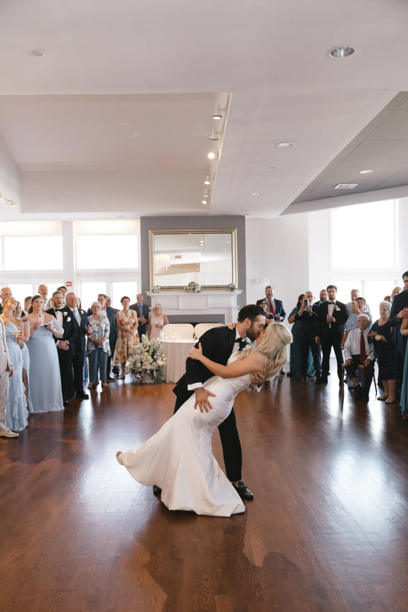 The groom dips the bride on the dance floor as guests look on