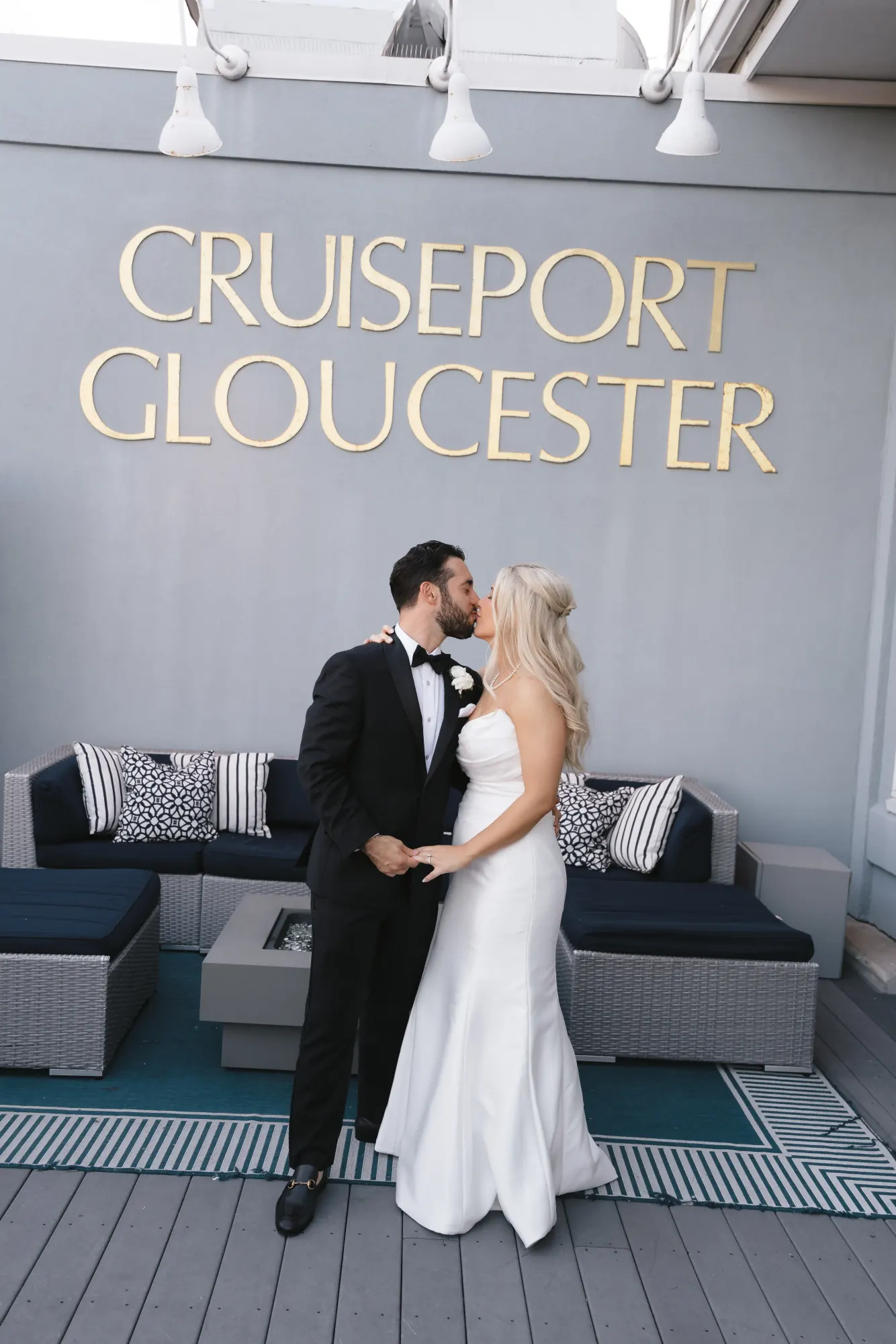 Bride and groom beneath the gold Cruiseport Gloucester sign