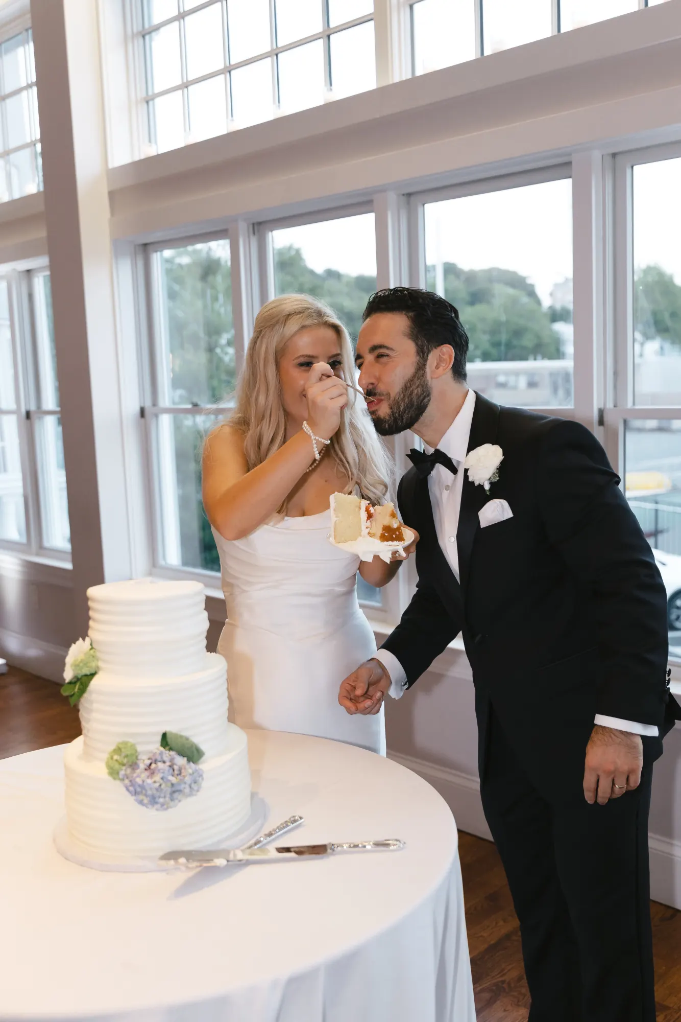 The bride laughs as the couple share a bite of wedding cake