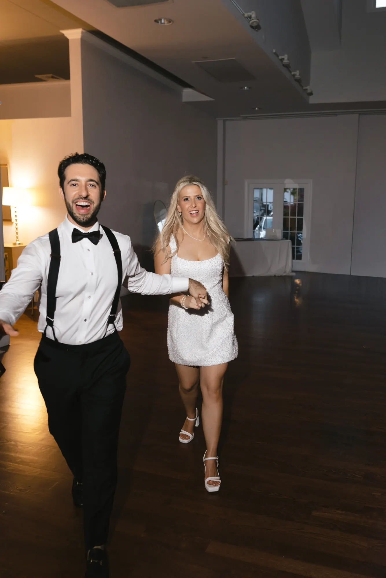 The couple return to the dance floor, the bride in a short white party dress