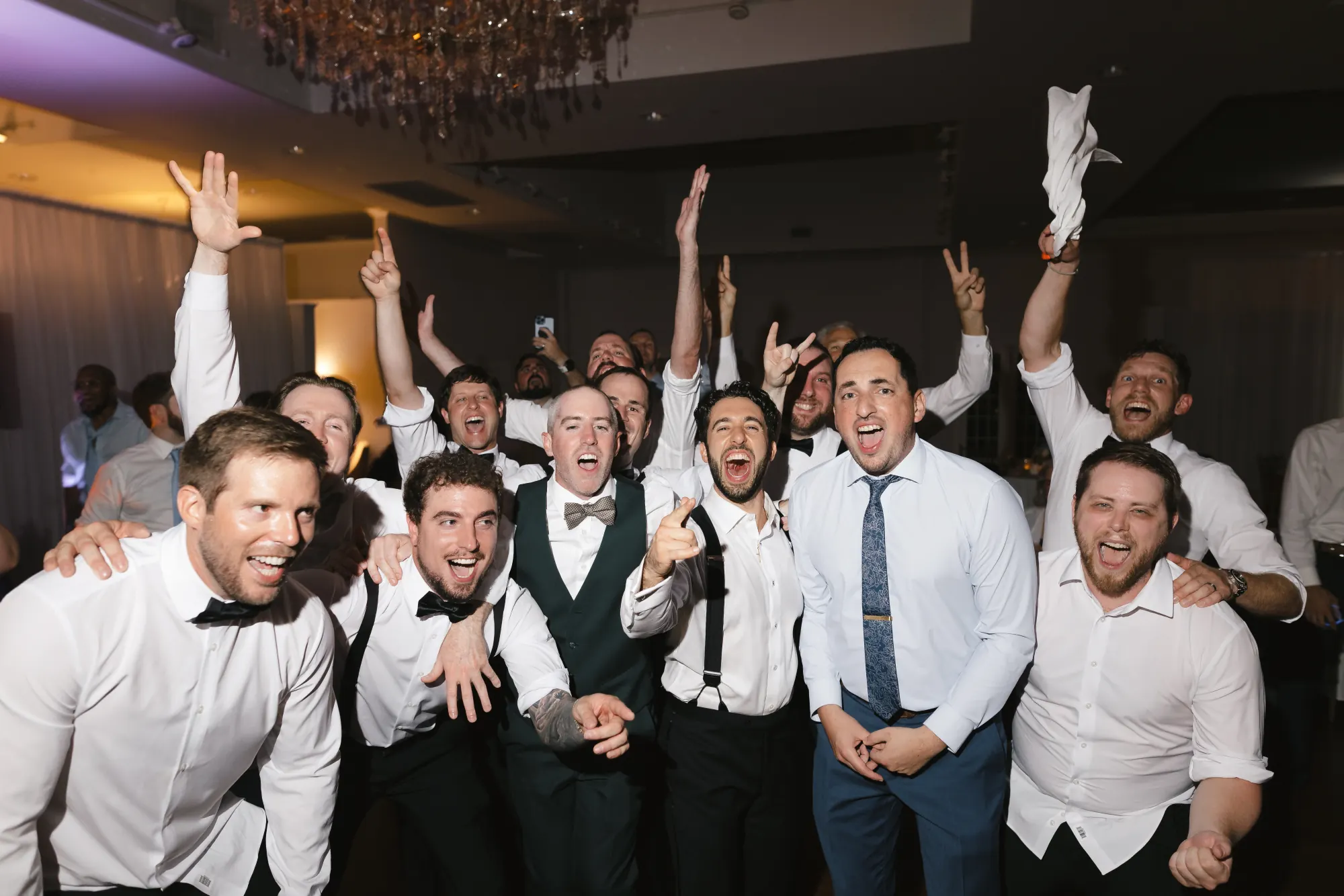 The guys throw their arms up for a group shot on the dance floor