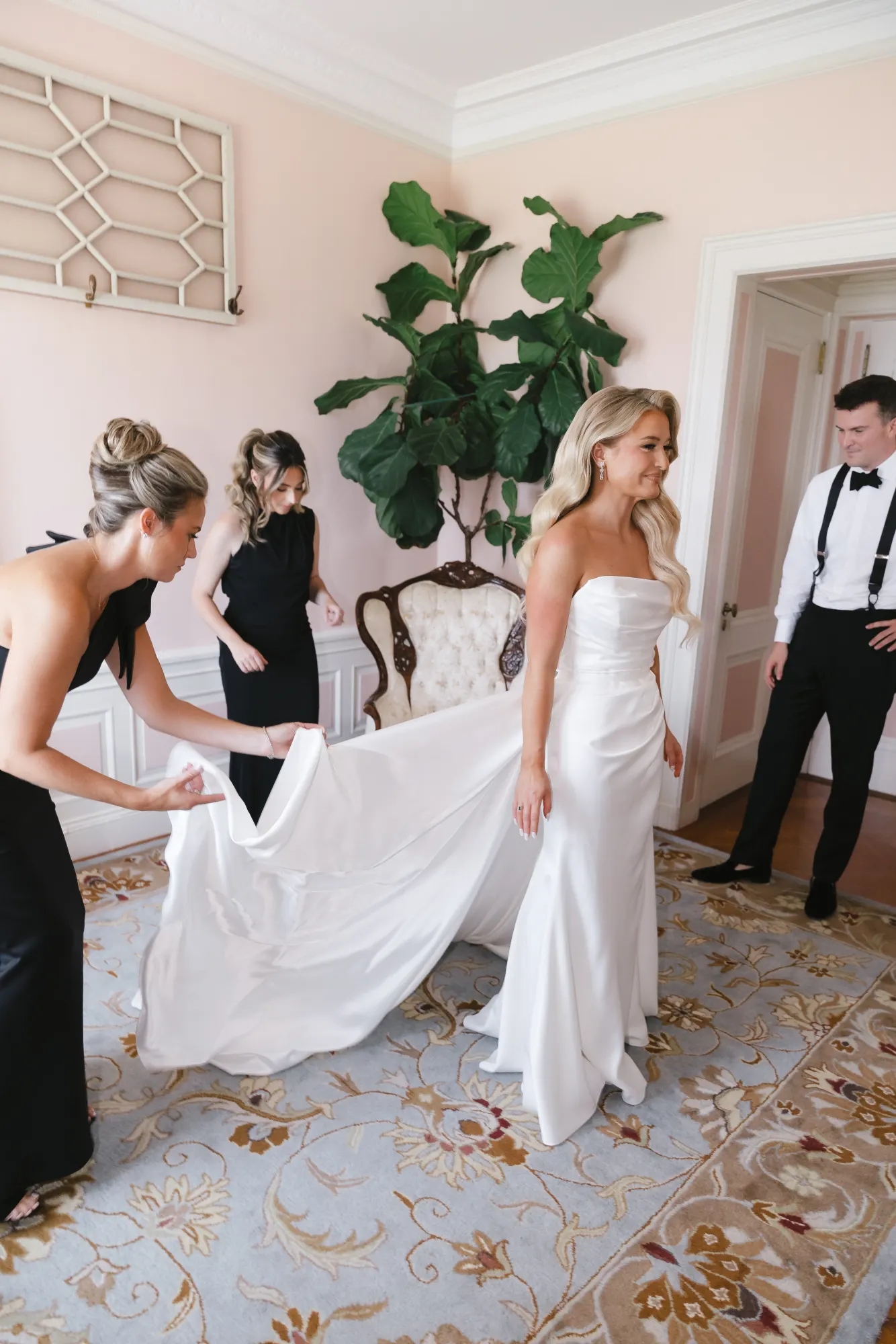 Bridesmaids in black arrange the train of the gown