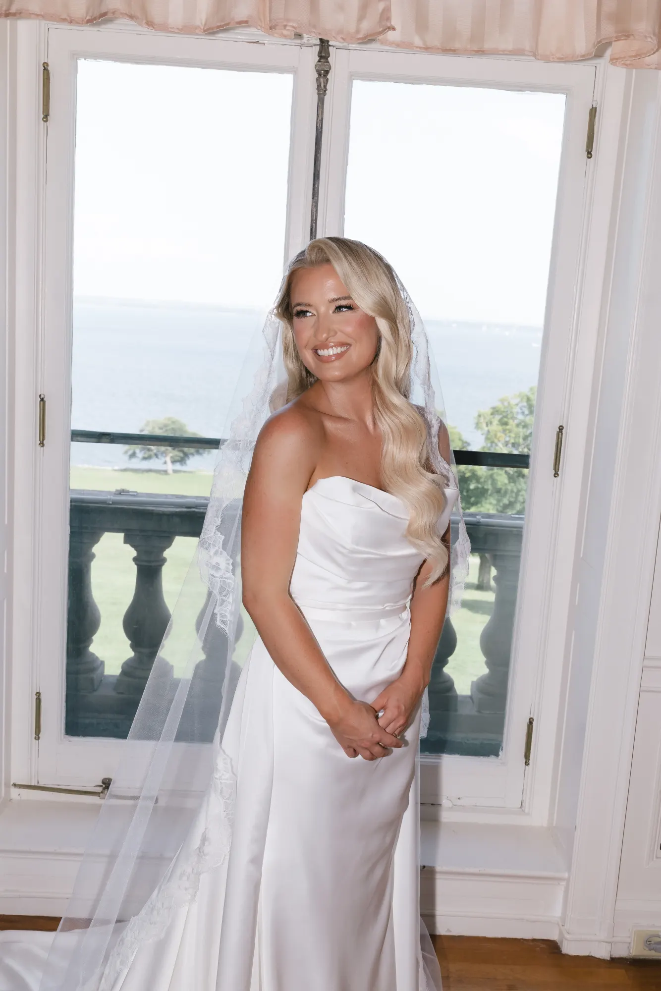The bride in the window light with Narragansett Bay behind her