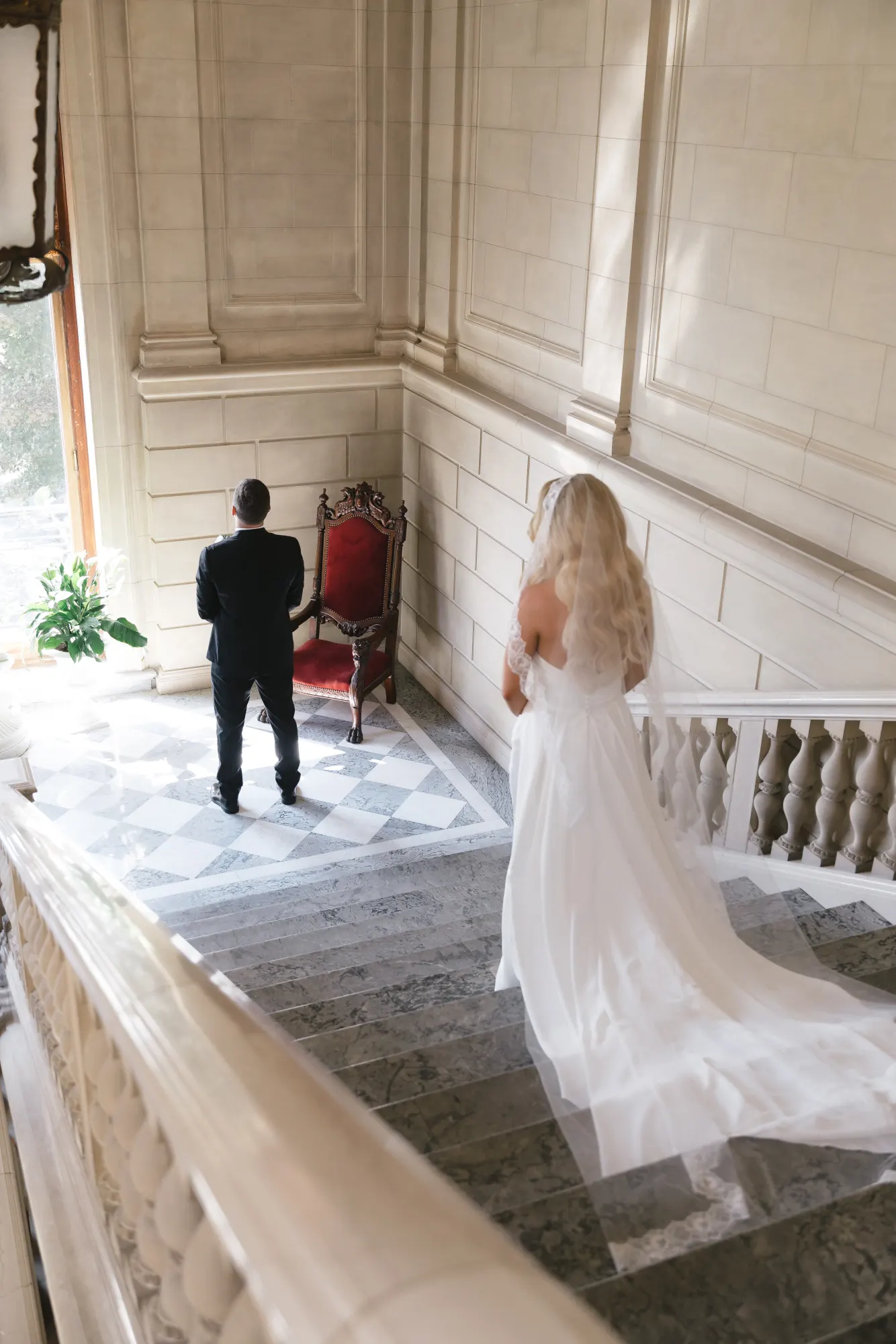 Max waits on the grand staircase landing as Colleen approaches for the first look