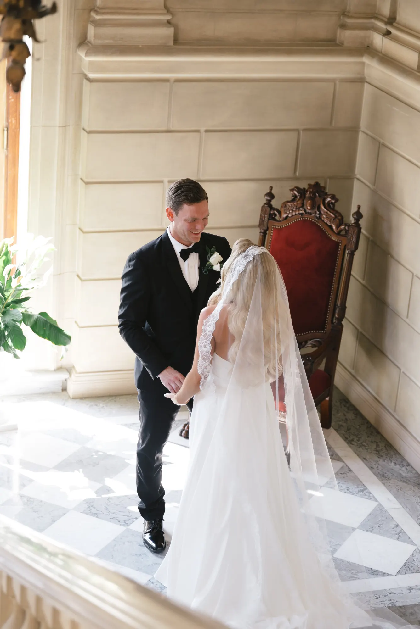 The couple holds hands on the staircase landing after the first look