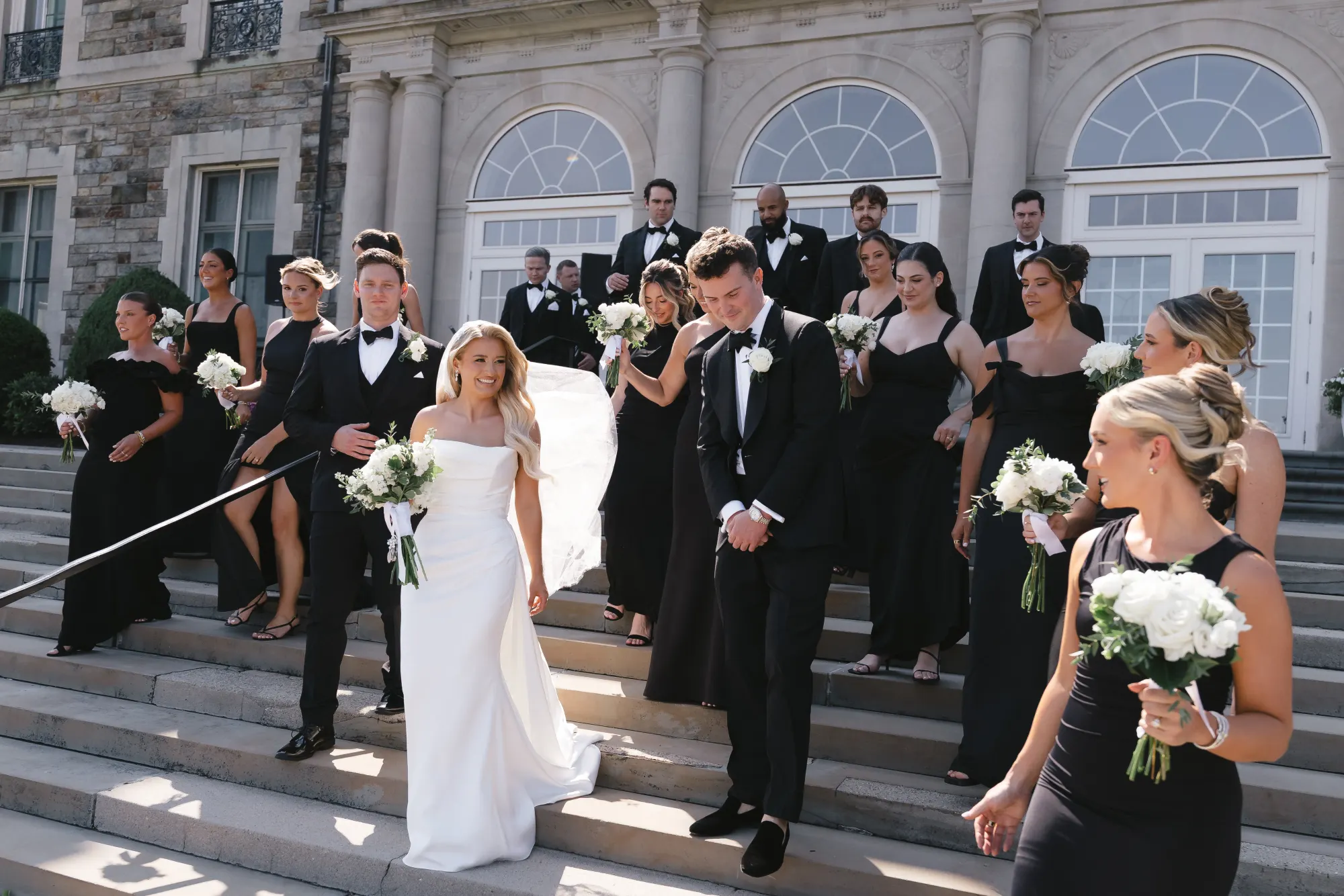 The full wedding party of 26 cheers on the terrace steps
