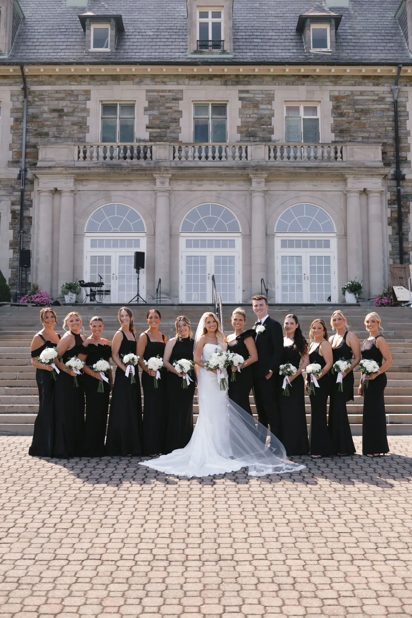 Colleen with her bridesmaids in black gowns holding white bouquets