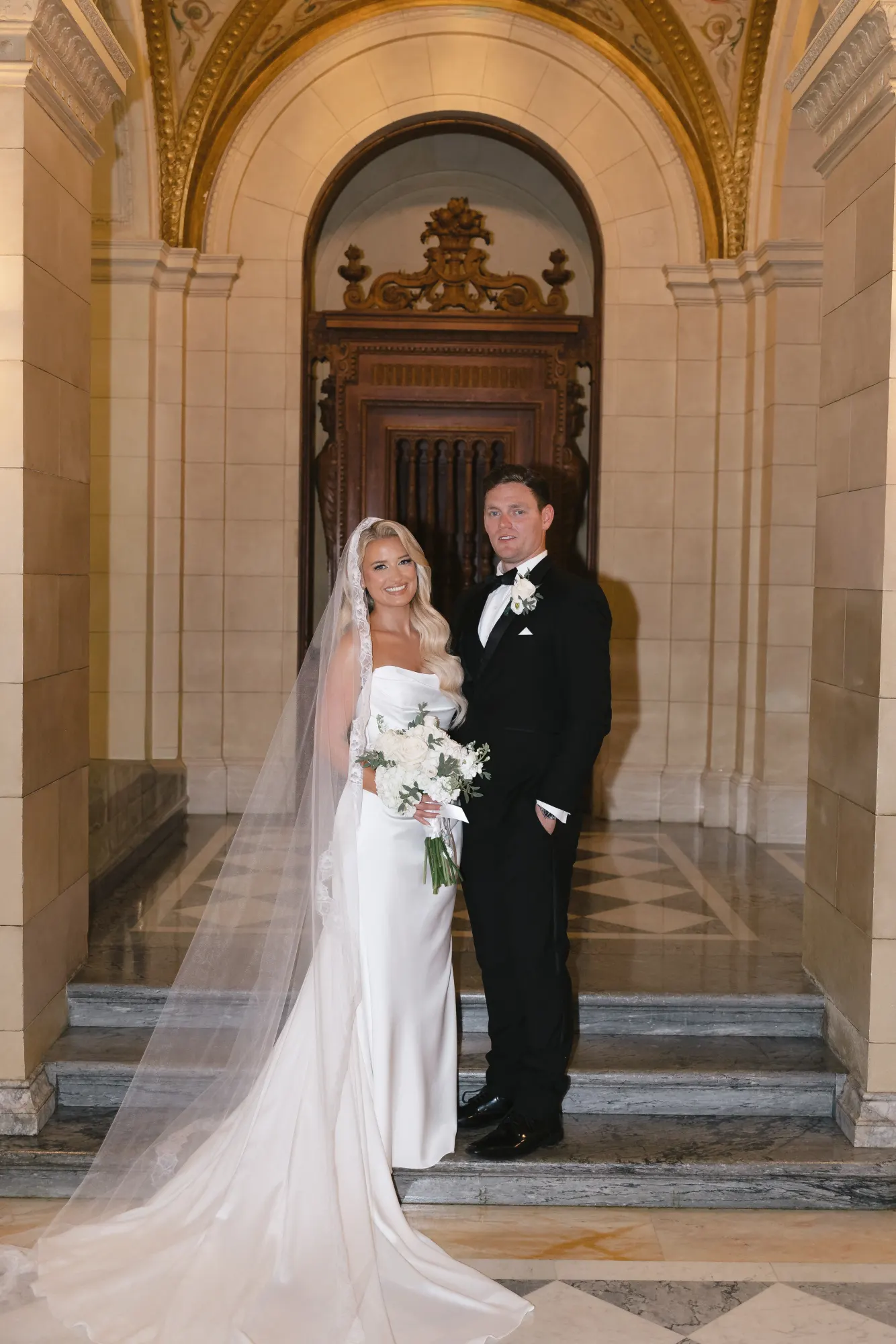 Formal portrait of the couple in the gilded arch of the chapel entrance