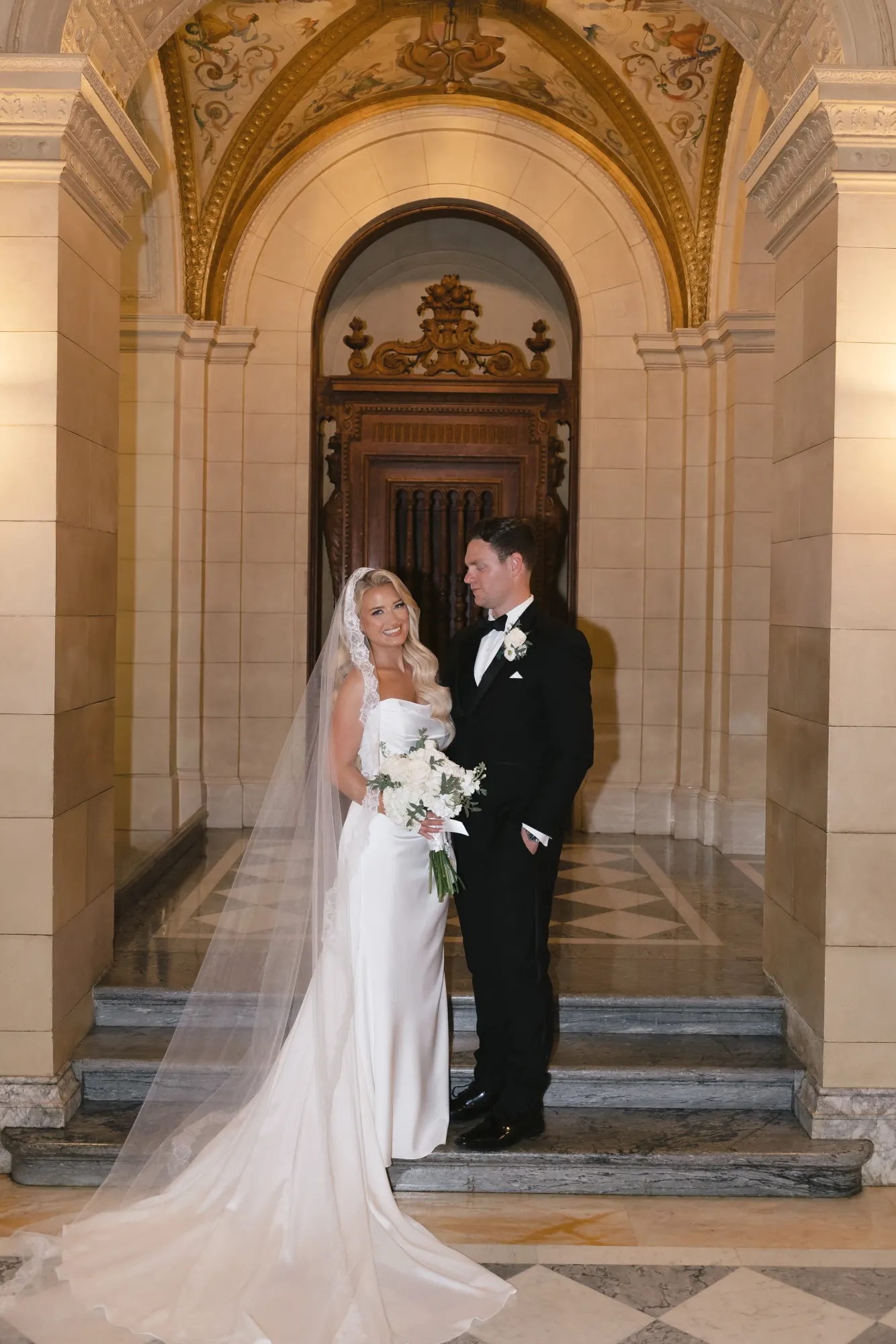 Bride and groom beneath the carved stone archway