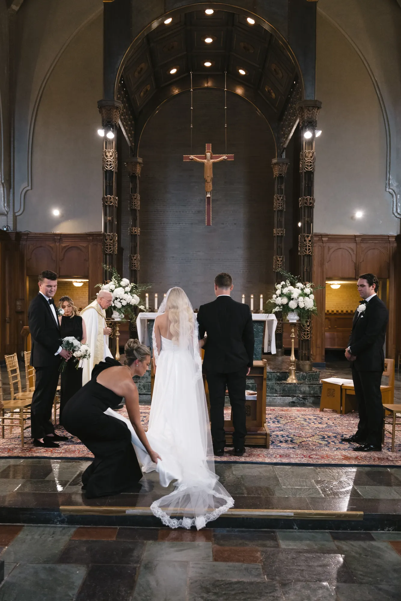 A bridesmaid sets the cathedral veil at the altar steps