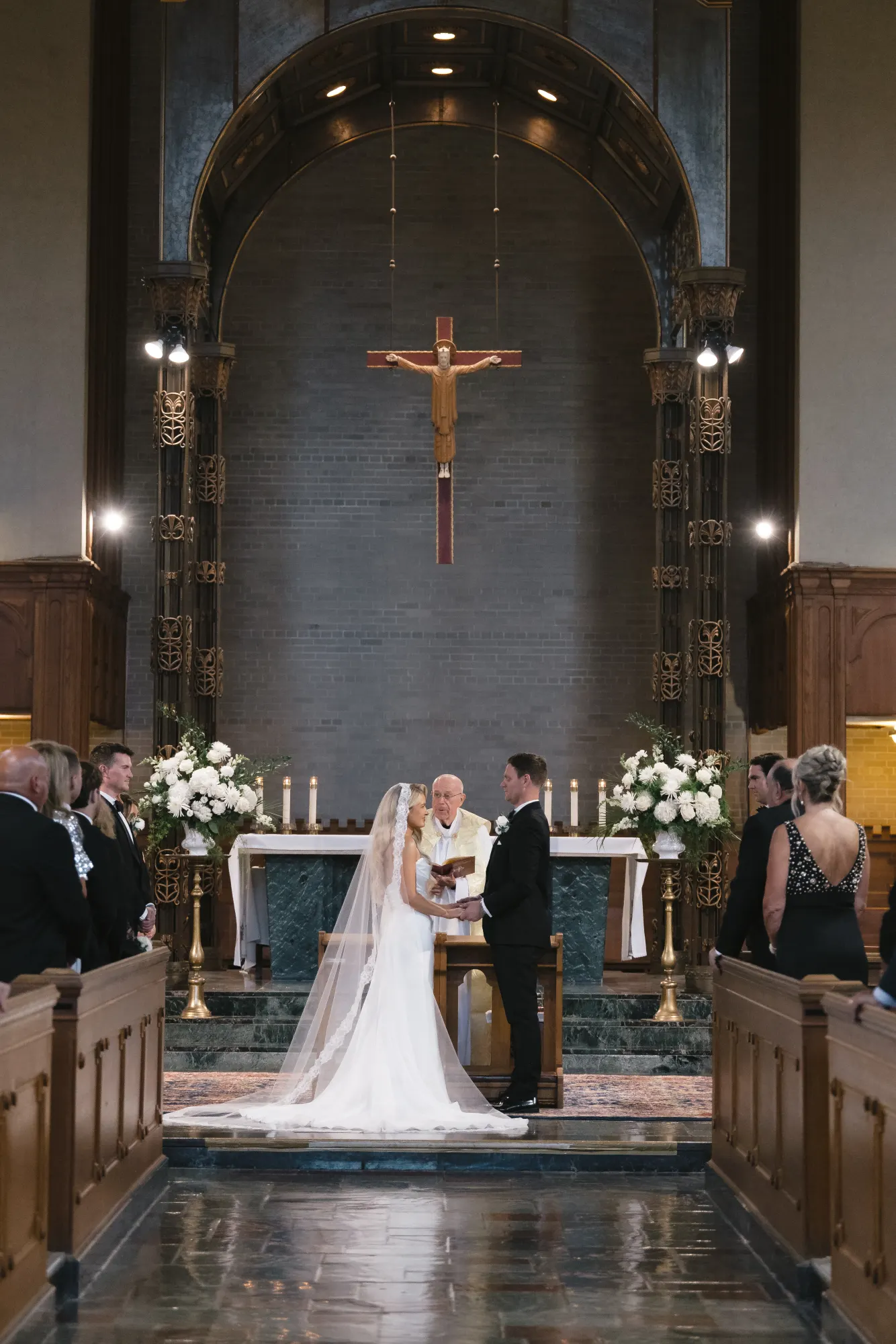 The couple at the marble altar beneath the crucifix
