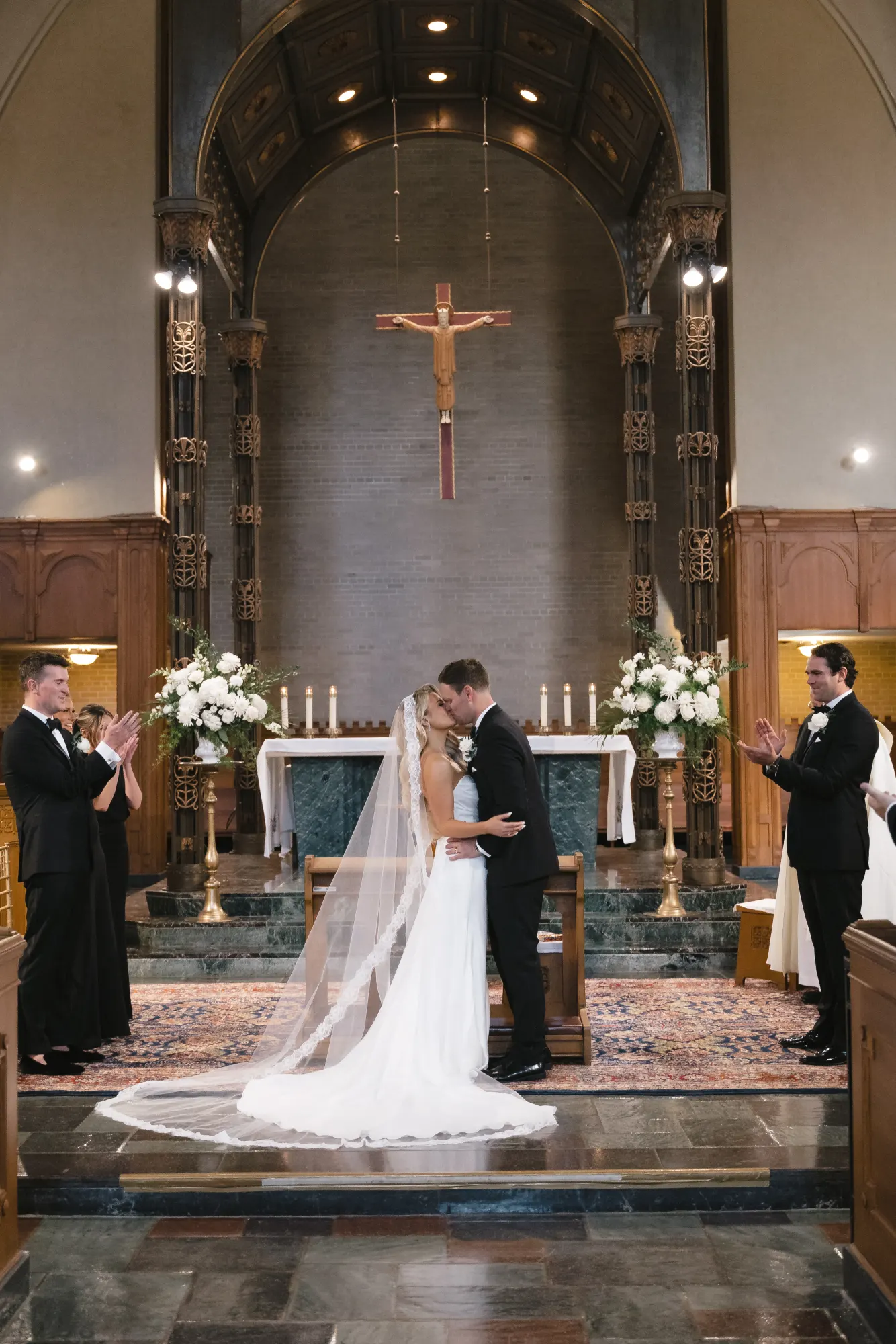 The wedding party applauds from the altar steps