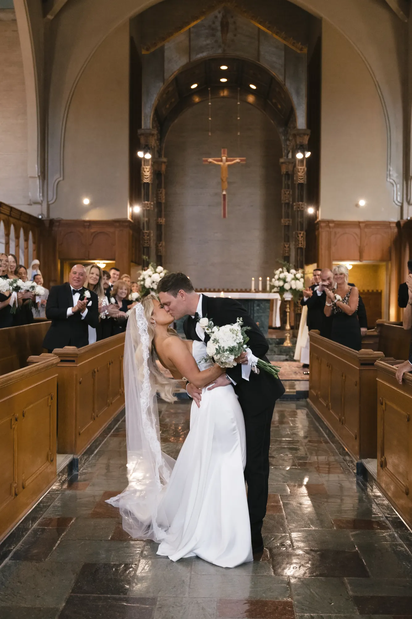 A recessional kiss in the aisle as guests cheer