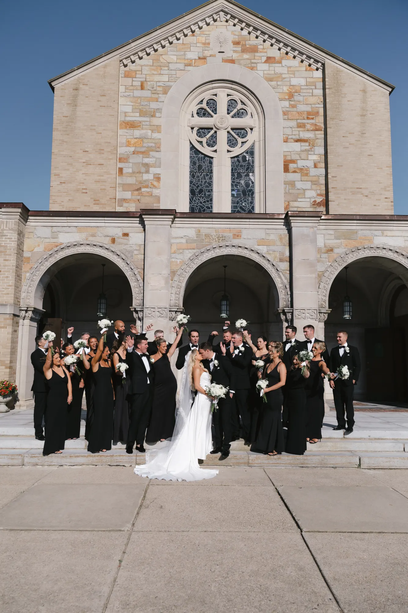 The wedding party cheers on the church steps outside the chapel