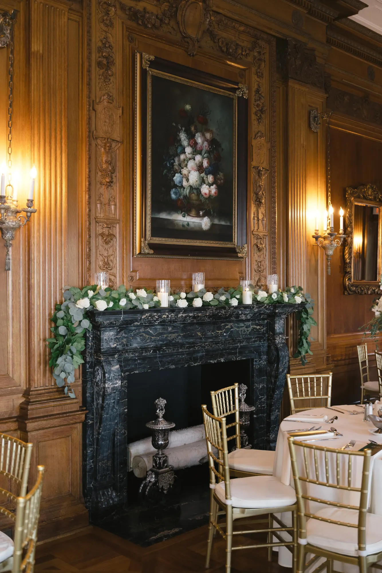 Carved paneling and a marble fireplace dressed in greenery and candles in the dining room