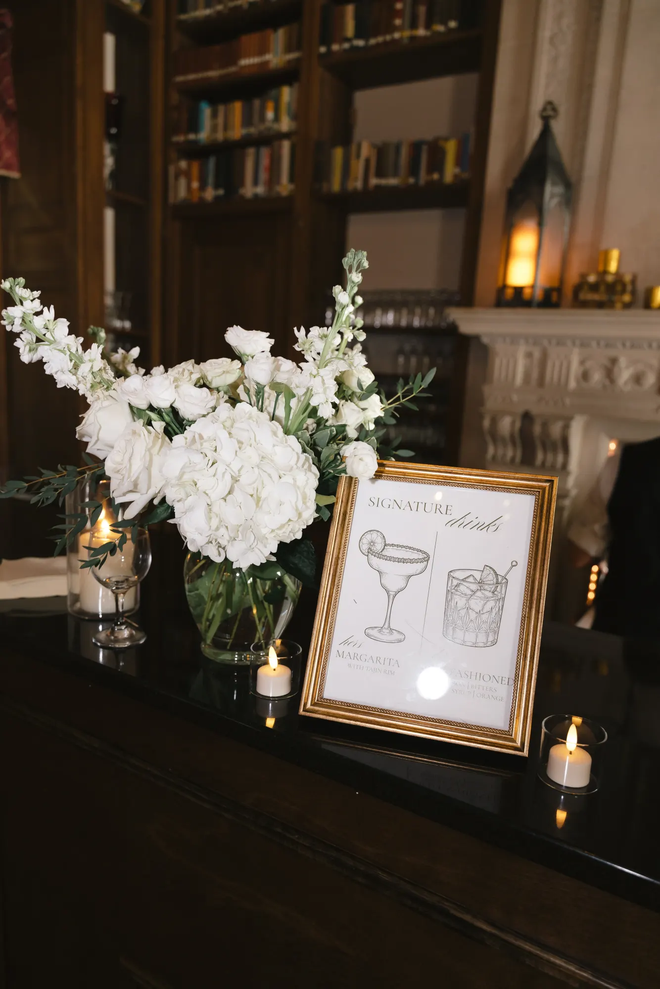 White florals and the signature drinks sign at the library bar