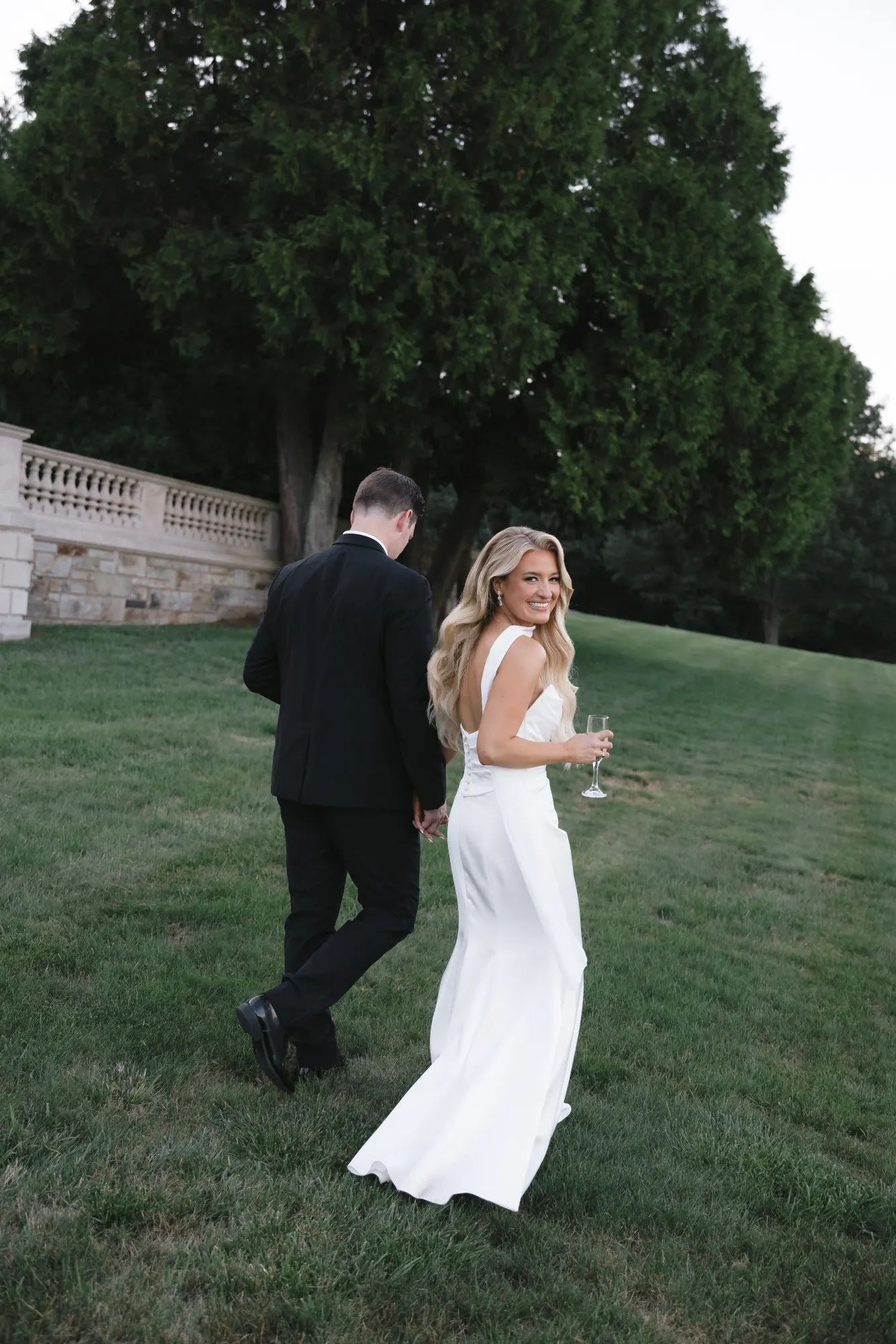 The couple slips away across the lawn at golden hour